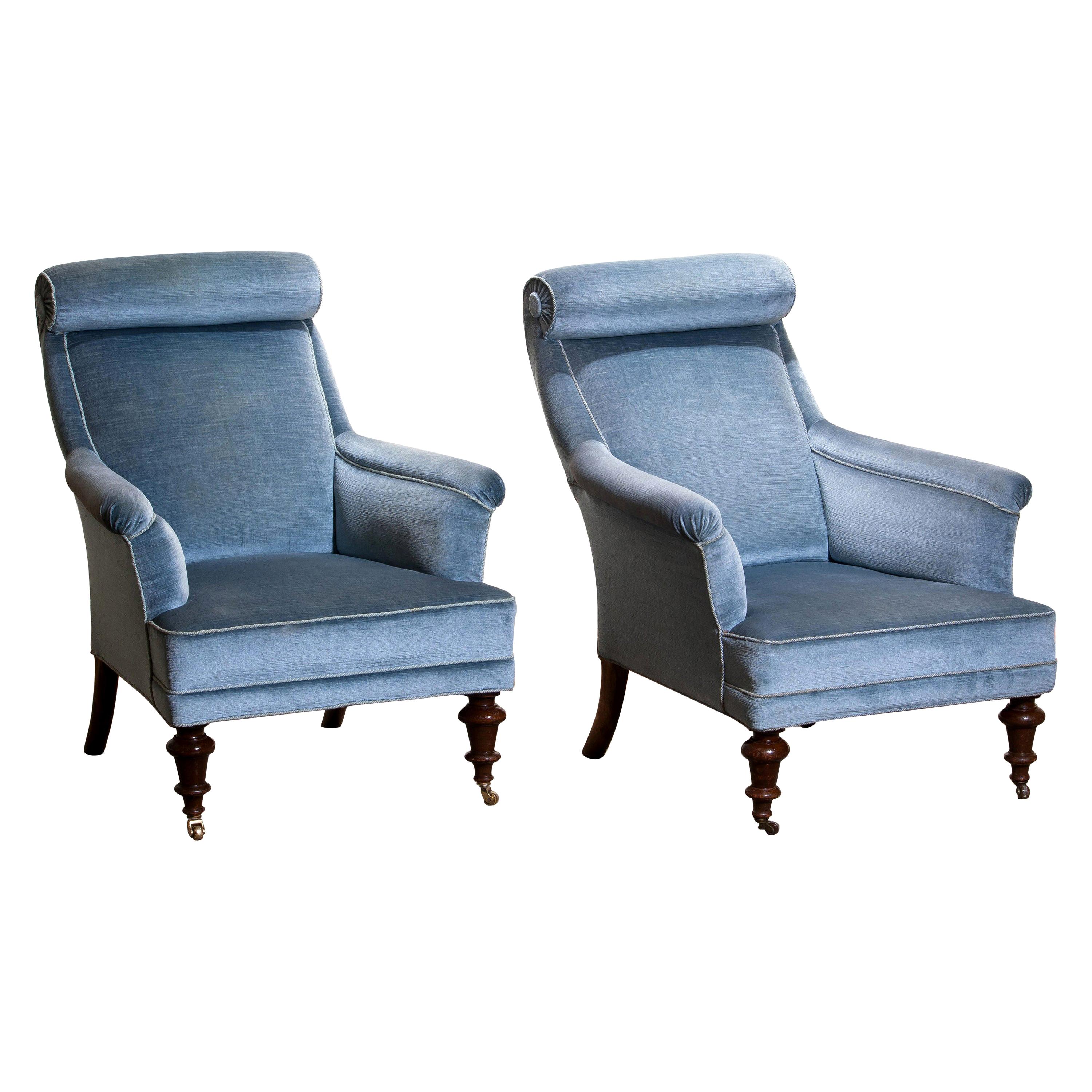 Rare and extremely comfortable / beautiful set of two bergere / lounge chairs in Dorothy Draper style from the turn to the 20th century.
Both chairs are upholstered in ice blue velvet and in good condition..

One chair has new wheels in brass and