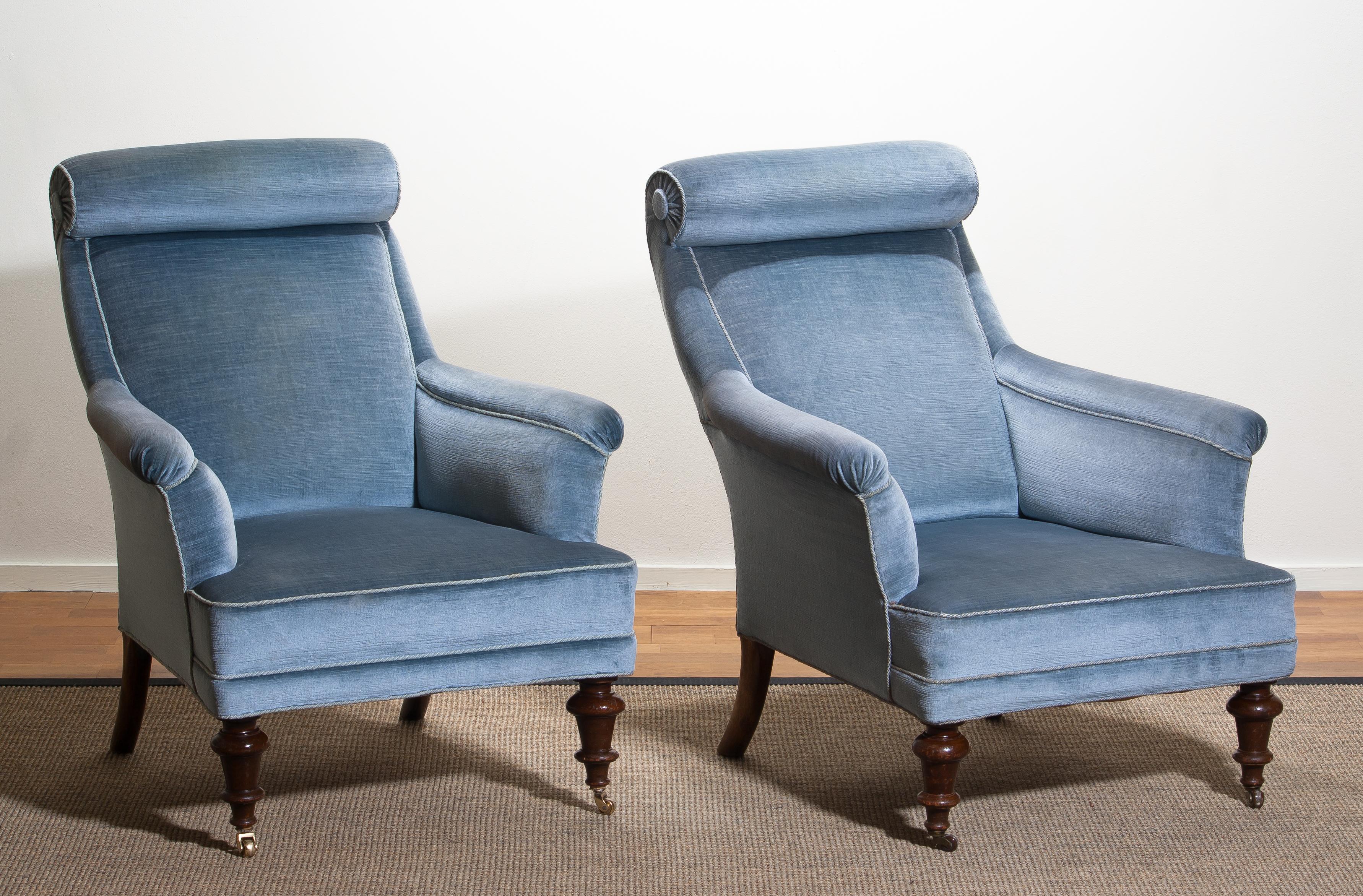 Rare and extremely comfortable / beautiful set of two bergère / lounge chairs in Dorothy Draper style from the turn to the 20th century.
Both chairs are upholstered in ice blue velvet and in good condition.

One chair has new wheels in brass and