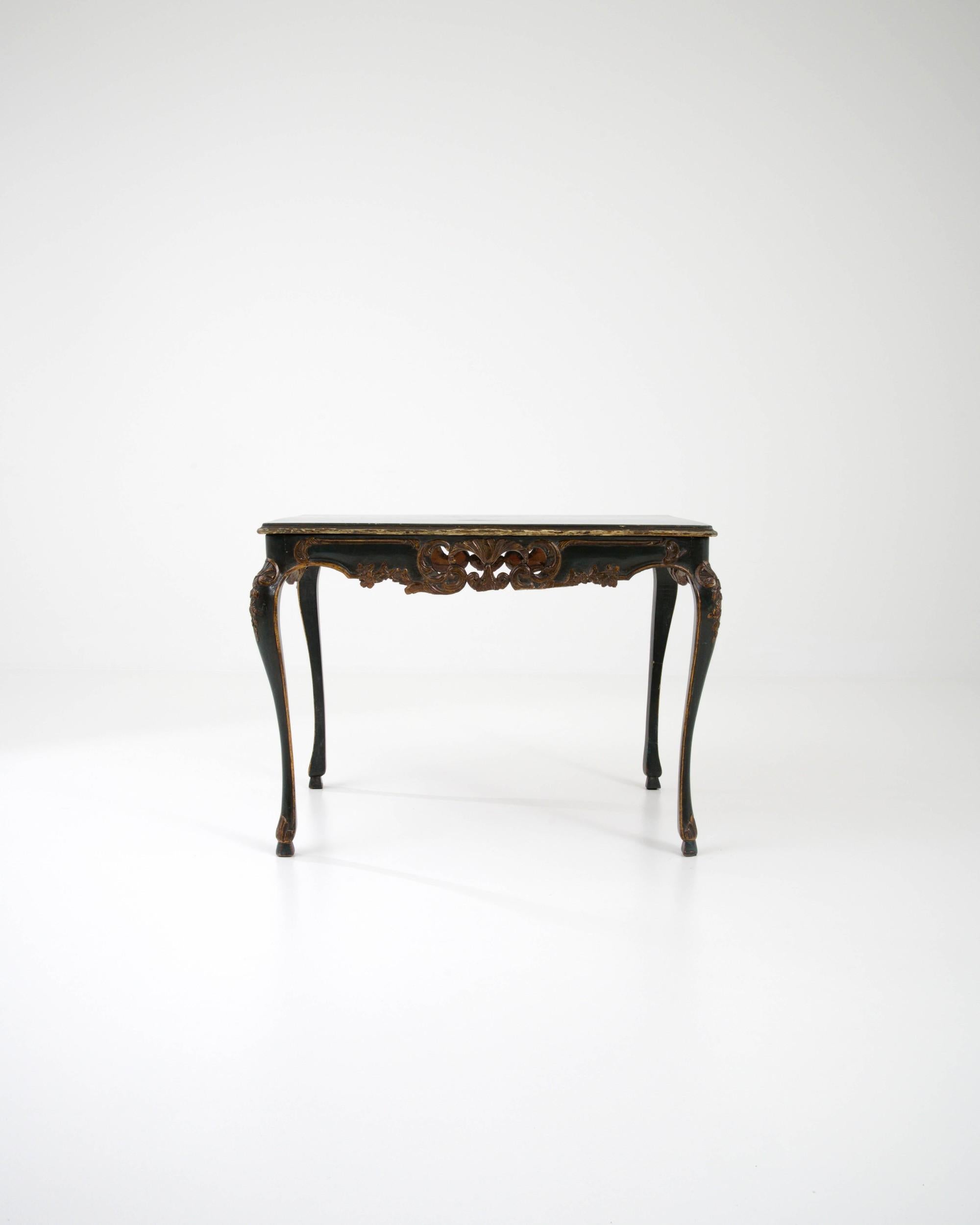 Handcrafted in Spain in the 1900s, this elegant wooden table features gracefully curved cabriole legs, which are richly detailed with ornate floral and foliate accents. These intricate carvings extend to the apron, creating a sense of abundance and