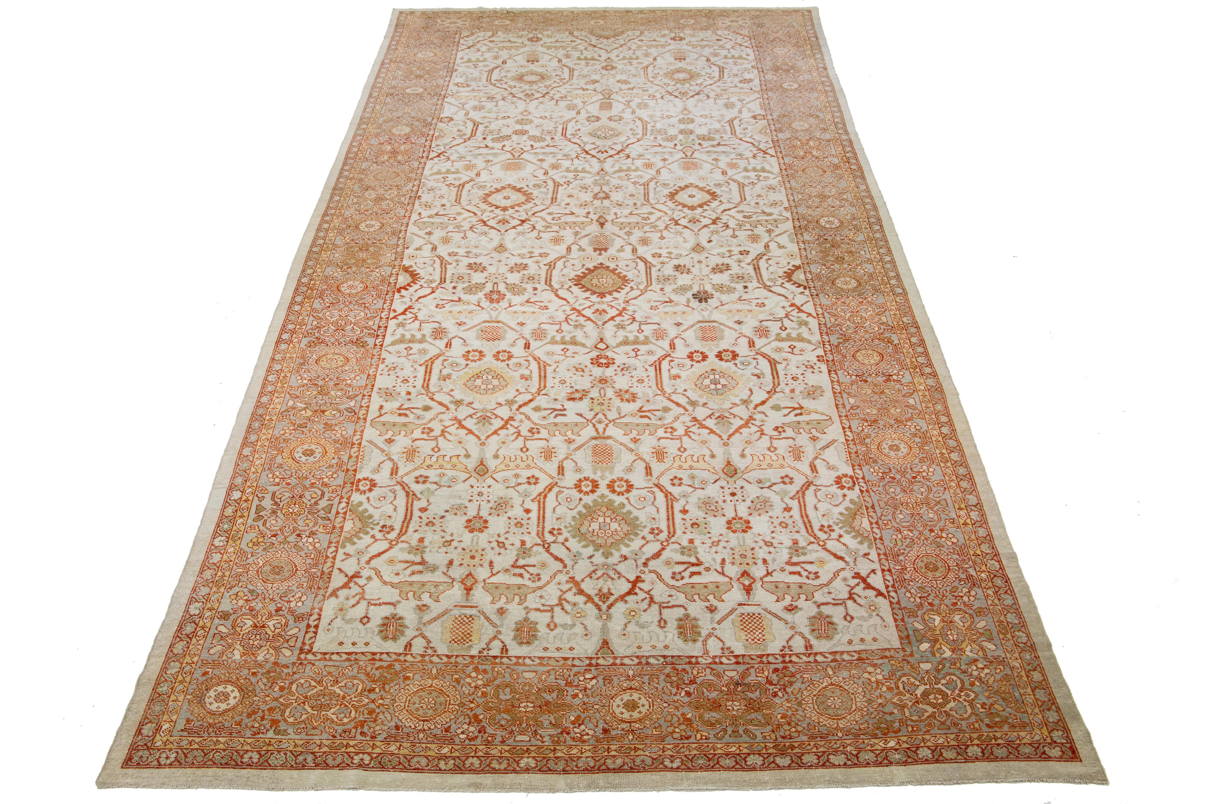 Beautiful antique Persian hand-knotted wool rug with a beige color field. This piece has a gray frame with orange and green accents in a gorgeous all-over floral design.

This rug measures 9'8