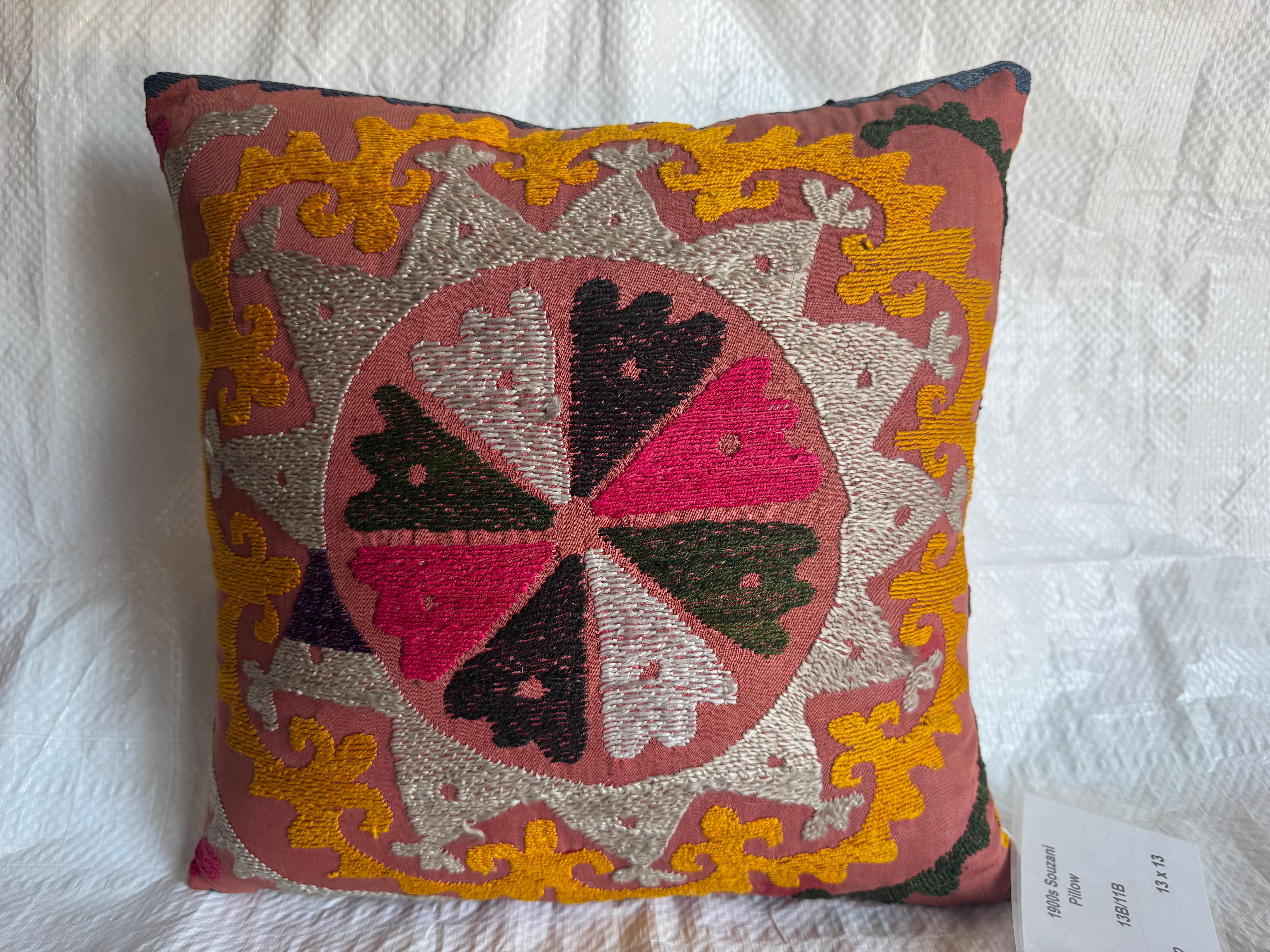 Ce vibrant coussin Suzani des années 1900 a été fabriqué à la main en utilisant des techniques de broderie traditionnelles transmises de génération en génération. Dotée d'un médaillon floral central à huit pétales dans des tons riches de fuchsia, de