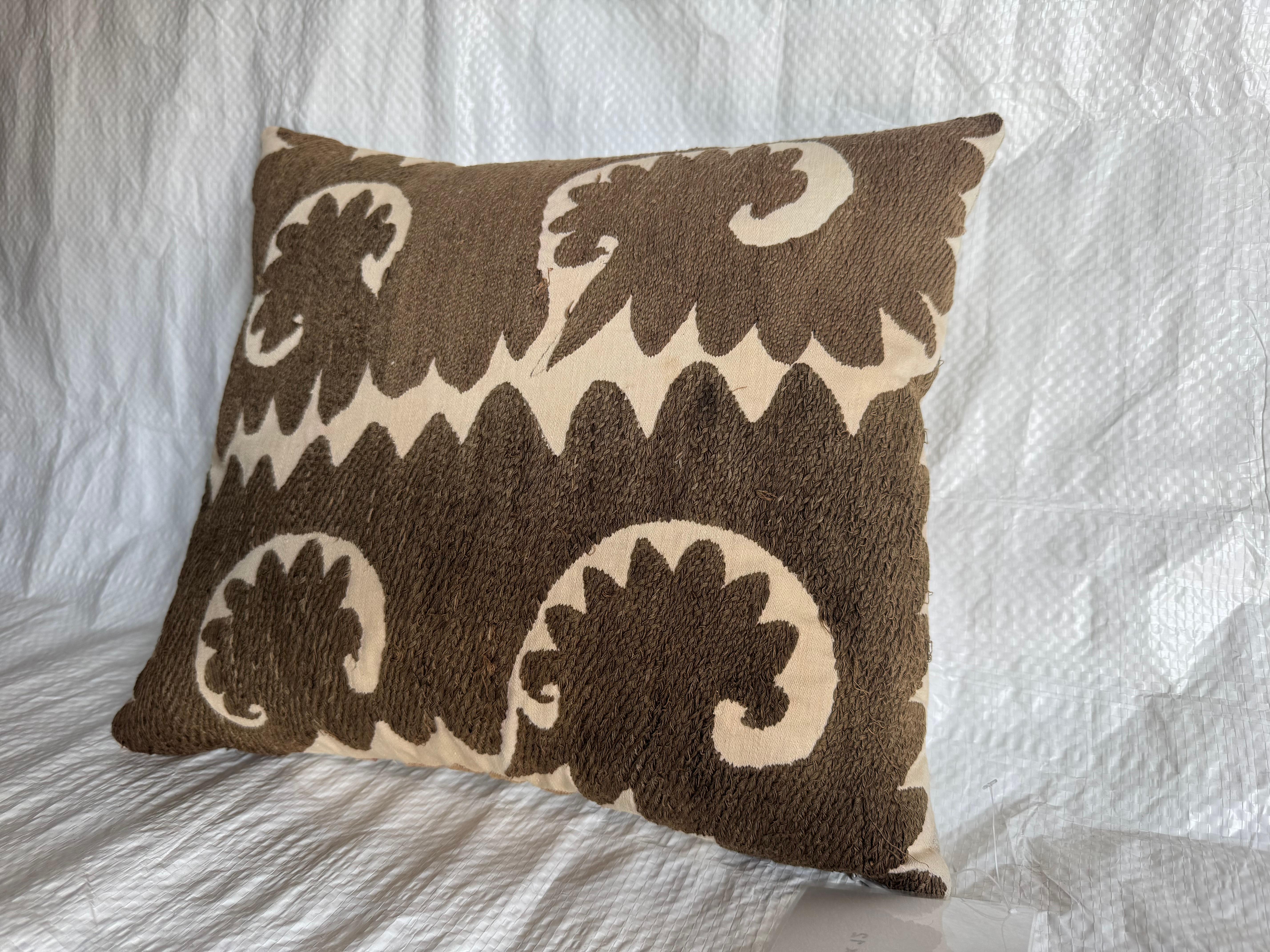 Un coussin décoratif saisissant fabriqué à partir d'un textile Suzani brodé à la main au début des années 1900, présentant un motif audacieux à grande échelle de couleur vert armée et ivoire. Le motif présente des formes abstraites et