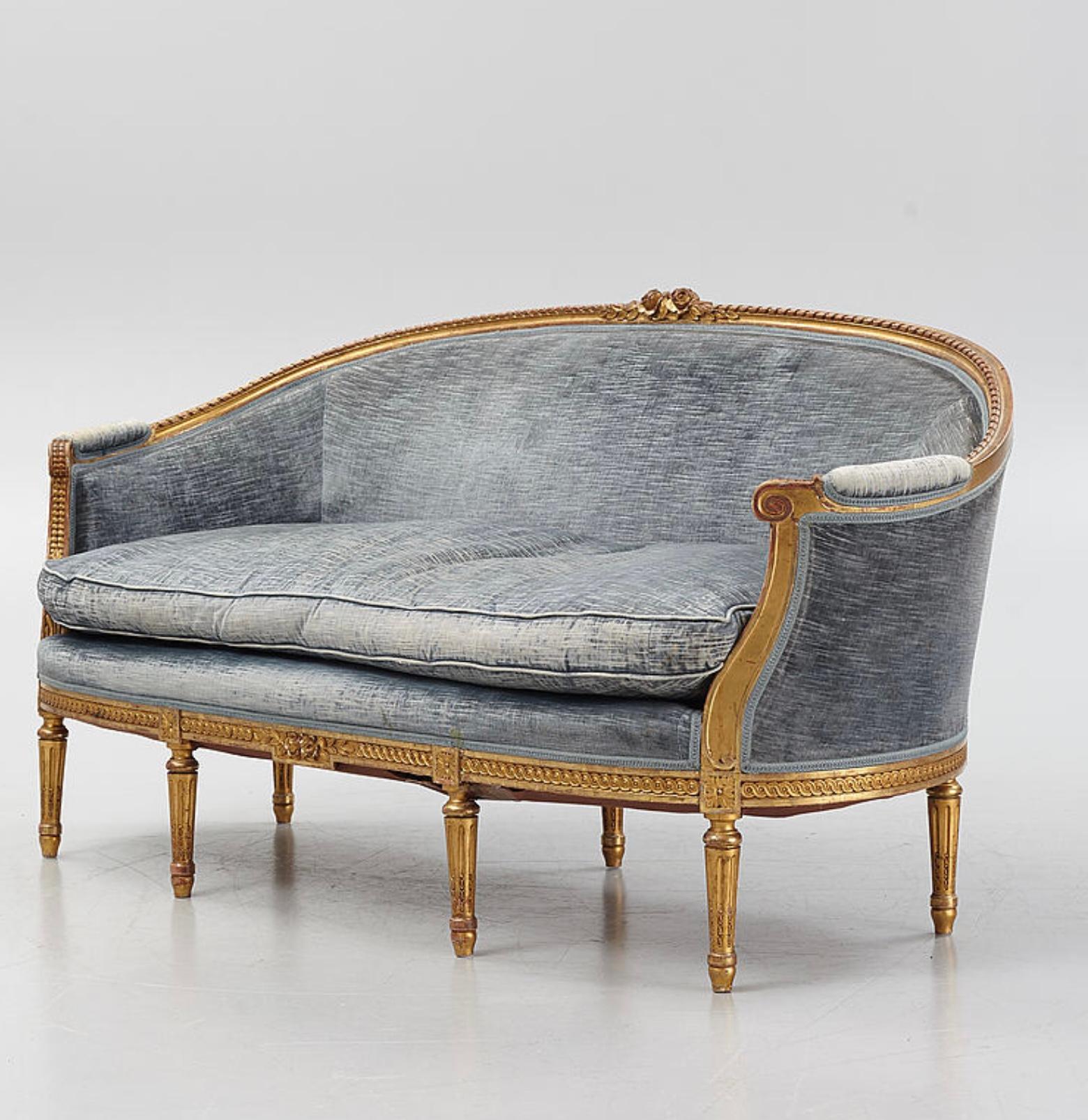 This wonderfully large and comfortable Swedish two-seater gilt sofa dates from the 1900s period and is designed in the Gustavian style.
The sofa features classic scrolling decoration with carved flowers and leaves at the centre and has a slightly