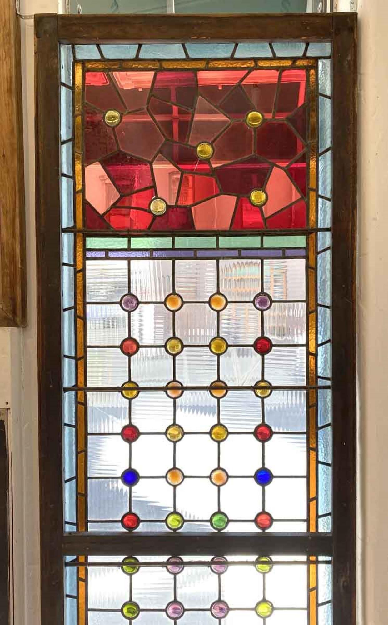 Very colorful early 1900s Victorian stained glass dark tone wood framed window with 61 round multi colored jewels and 8 pressed glass floral panels. The window has a number of stress cracks mostly to the clear panes, but is overall intact. Please
