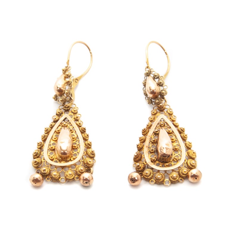 Pair of 14 karat gold dangle earrings crafted with a rich design of fine filigree and cannetille work. The earrings are very skillfully handcrafted. Each earring has two small balls dangling below the top. 

These kinds of jewels represent a varied