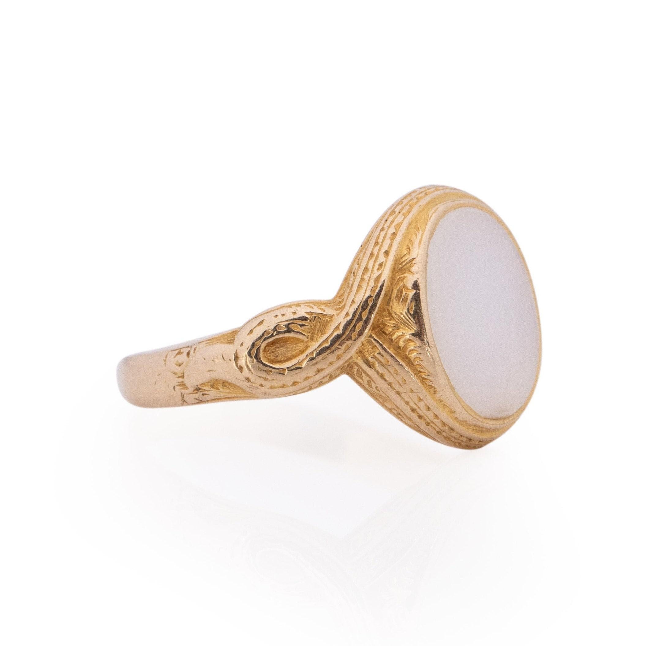 Introducing a one-of-a-kind vintage gem, this ring showcases exquisite craftsmanship in 15K yellow gold, featuring a milky-colored opaque oval gem at its center reminiscent of a moonstone. The sleek finish offers a subtle profile, allowing the