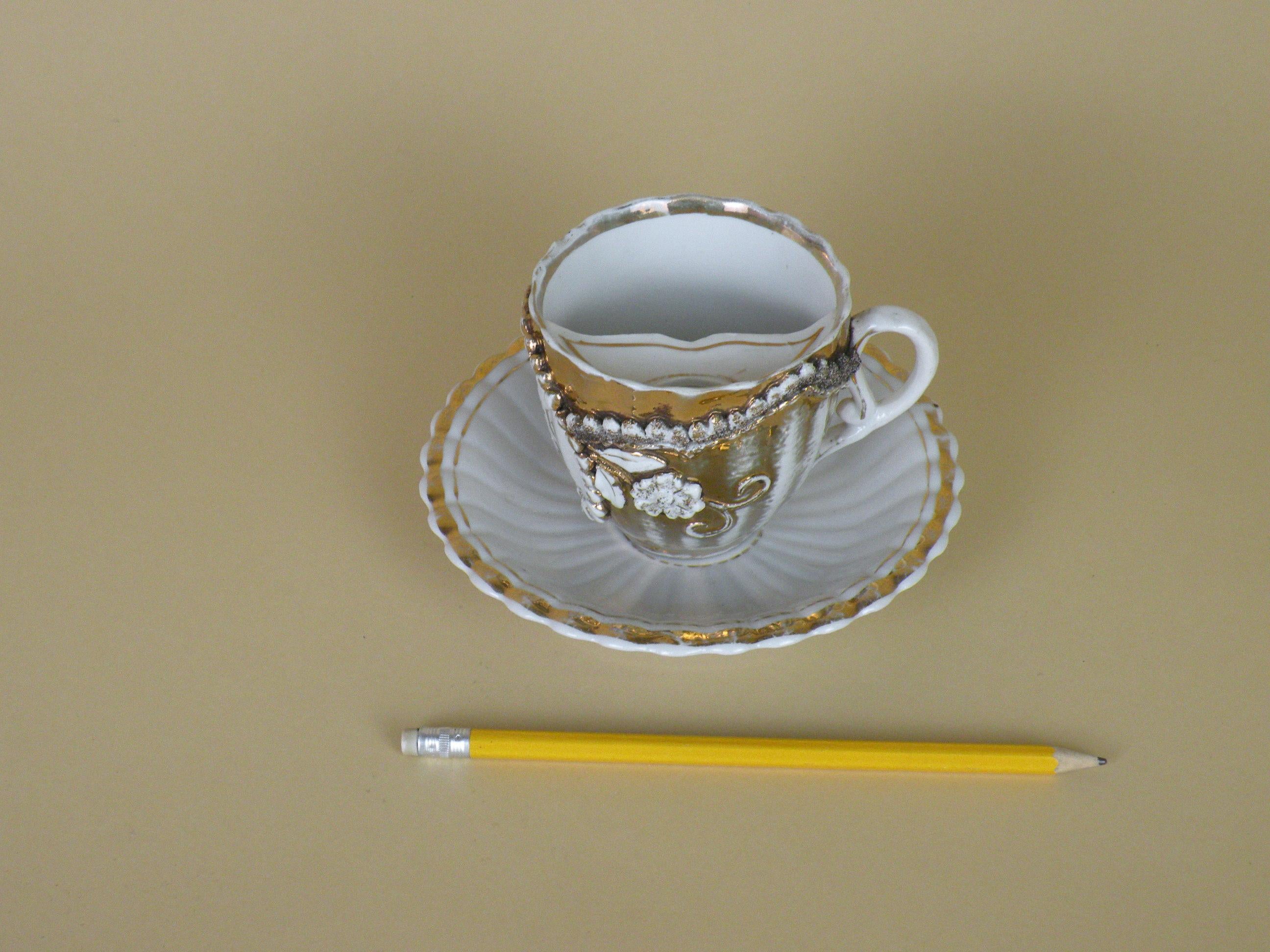 Early 20th century partially gilded white porcelain souvenir mustache cup with matching saucer. 

The cup have a circular geometrical motive and the writing 
