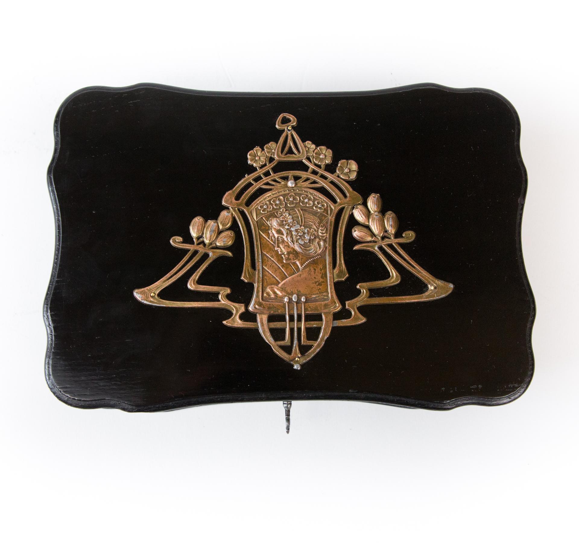 A beautiful Art Nouveau box with openwork application in the Art Nouveau style. Made like a large jewelry brooch. The application pattern is emphasized by ebony black and shine of noble polish.

The wooden casket is an example of Art Nouveau