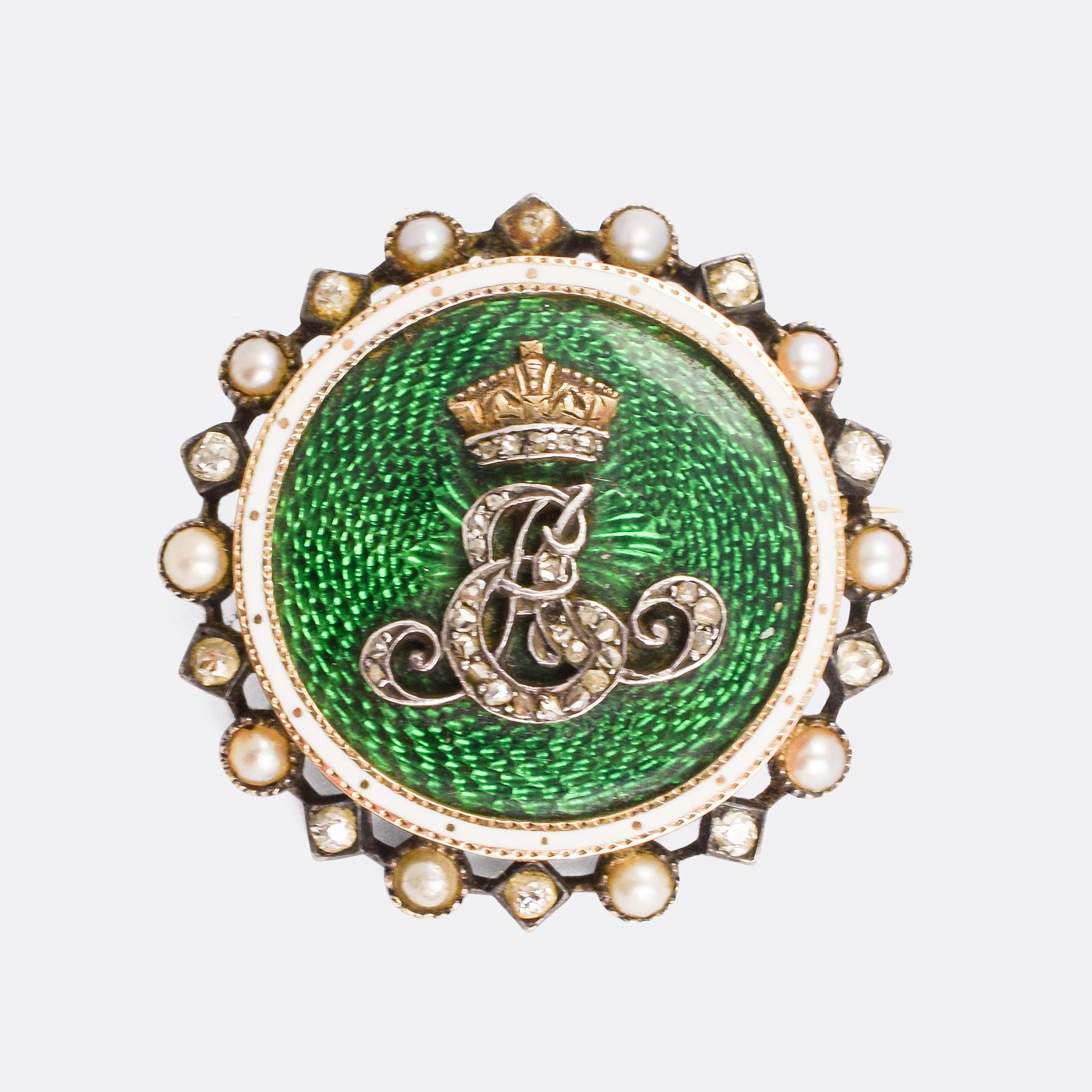 An especially lovely Edwardian  pendant and brooch suite with the original tooled leather presentation box. The pieces both feature stunning green guilloché enameling within a white enamel border, and to the centre royal cypher of King Edward VII.