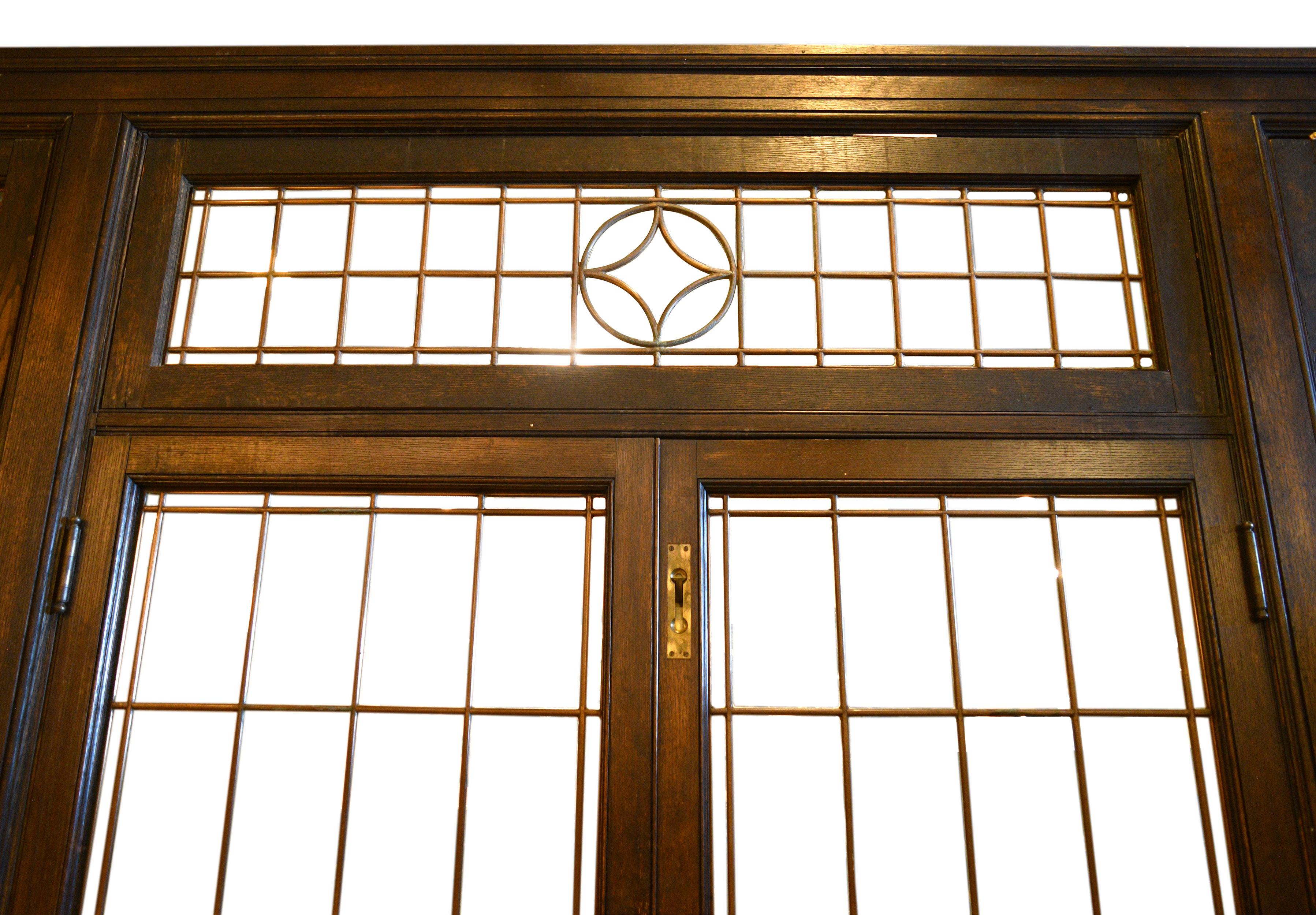 This gorgeous paneled wood dining room features several eye-catching details- a leaded glass door unit, two built in corner cabinets, large window opening, a built-in sideboard, and three different doorways. The doorway closest to the corner