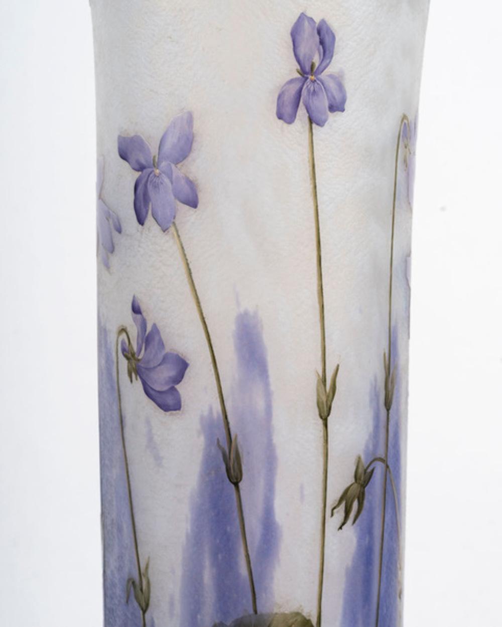 DAUM NANCY Large flared-neck roller vase with circular pedestal in lined glass with acid-etched and enamelled decoration of violet flowers in polychrome on an opaque violet-blue ground and enhanced with gilding Signed below the base “Daum Nancy”