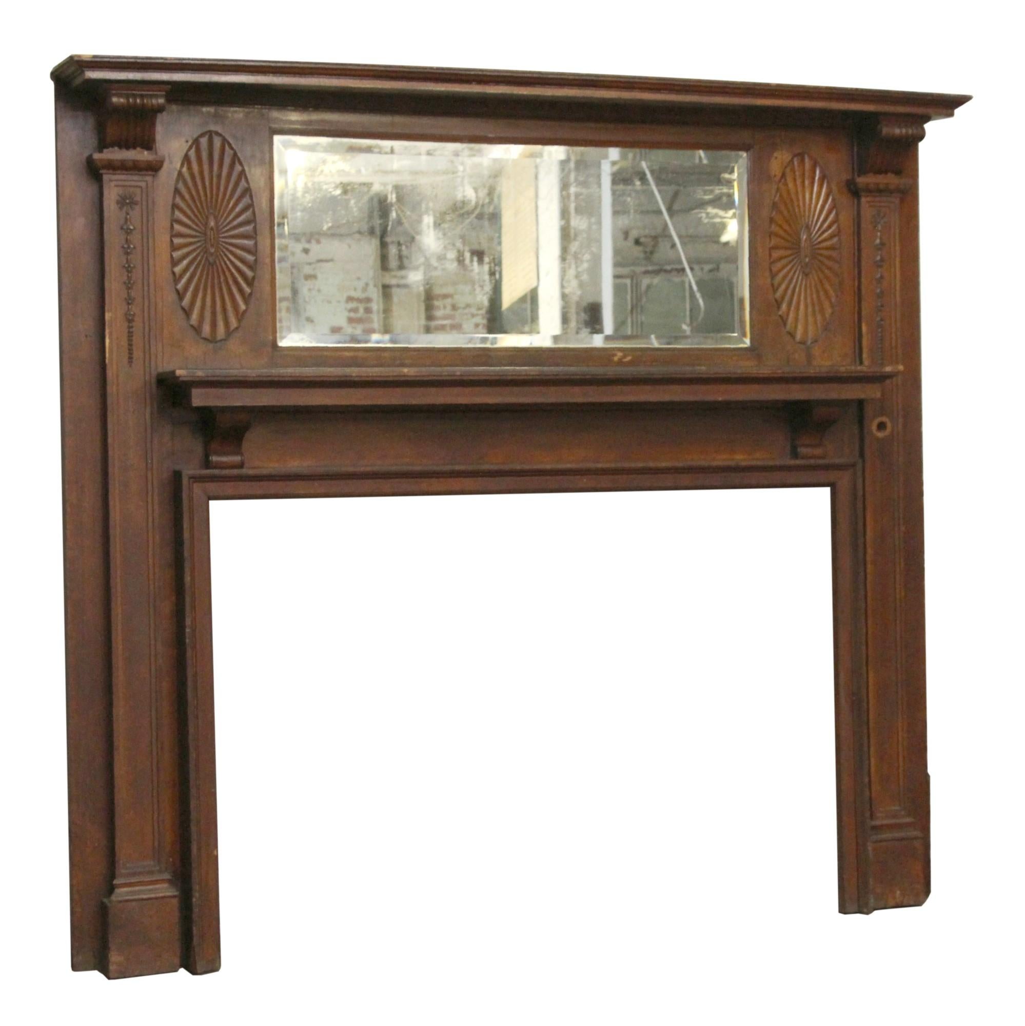 Dark wood tone traditional style mantel with horizontal beveled mirror and carved details from 1905. There is some wear and nicks in the wood from age and use. This can be seen at our 400 Gilligan St location in Scranton, PA.