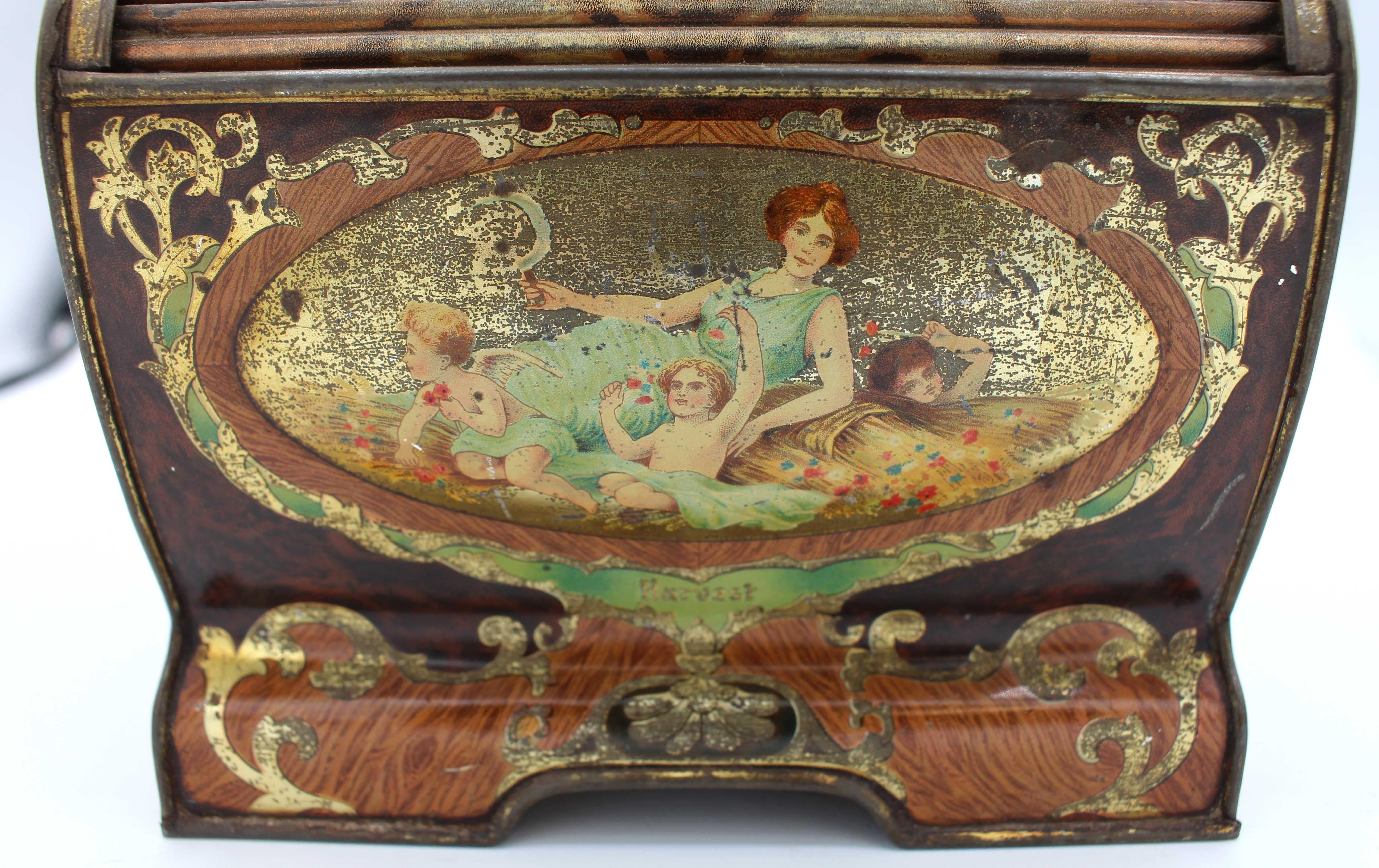 Famed 1906 Boîte en fer-blanc de forme cascade Art Nouveau par Huntley & Palmer, anglais. Chaque face est décorée de réserves figuratives gréco-romaines représentant la 
