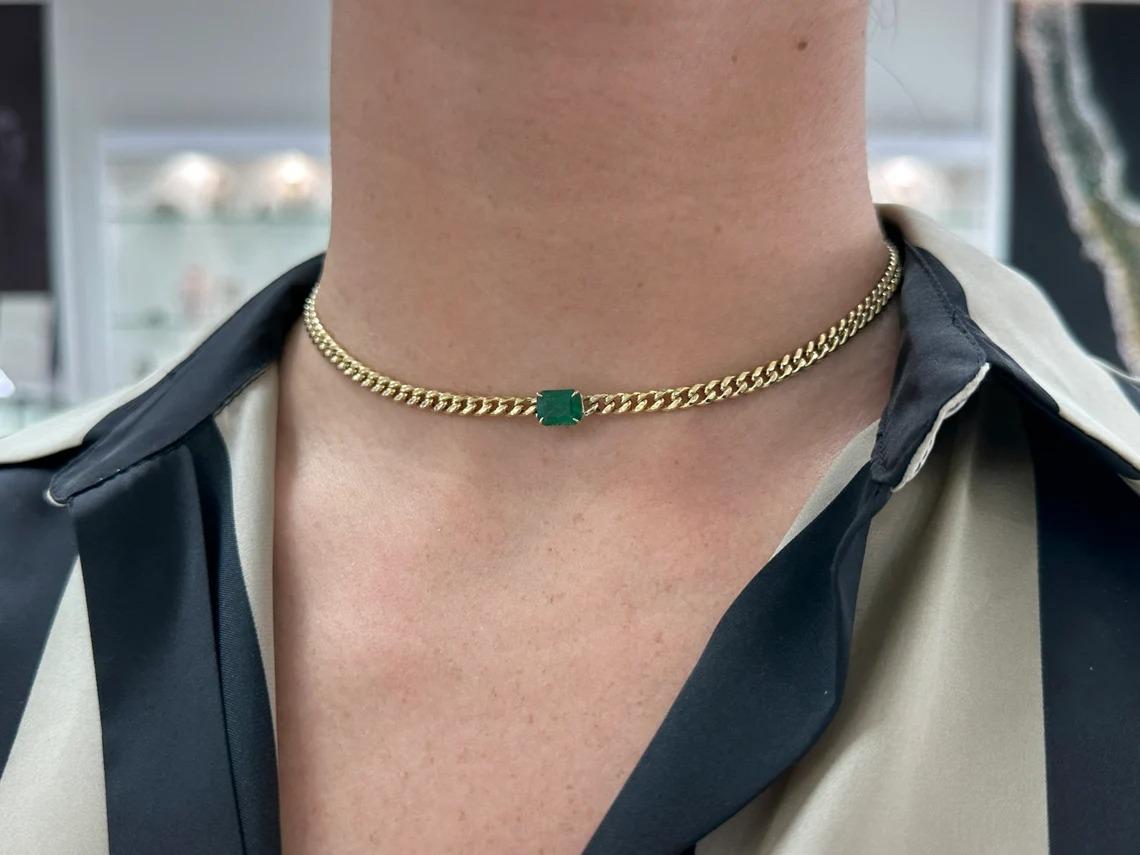 A remarkable emerald necklace in gold. This extravagant piece features a stunning natural emerald cut emerald that showcases a rich dark green color and very good clarity and luster. Set in a secure four-prong claw setting, attached to a lovely,