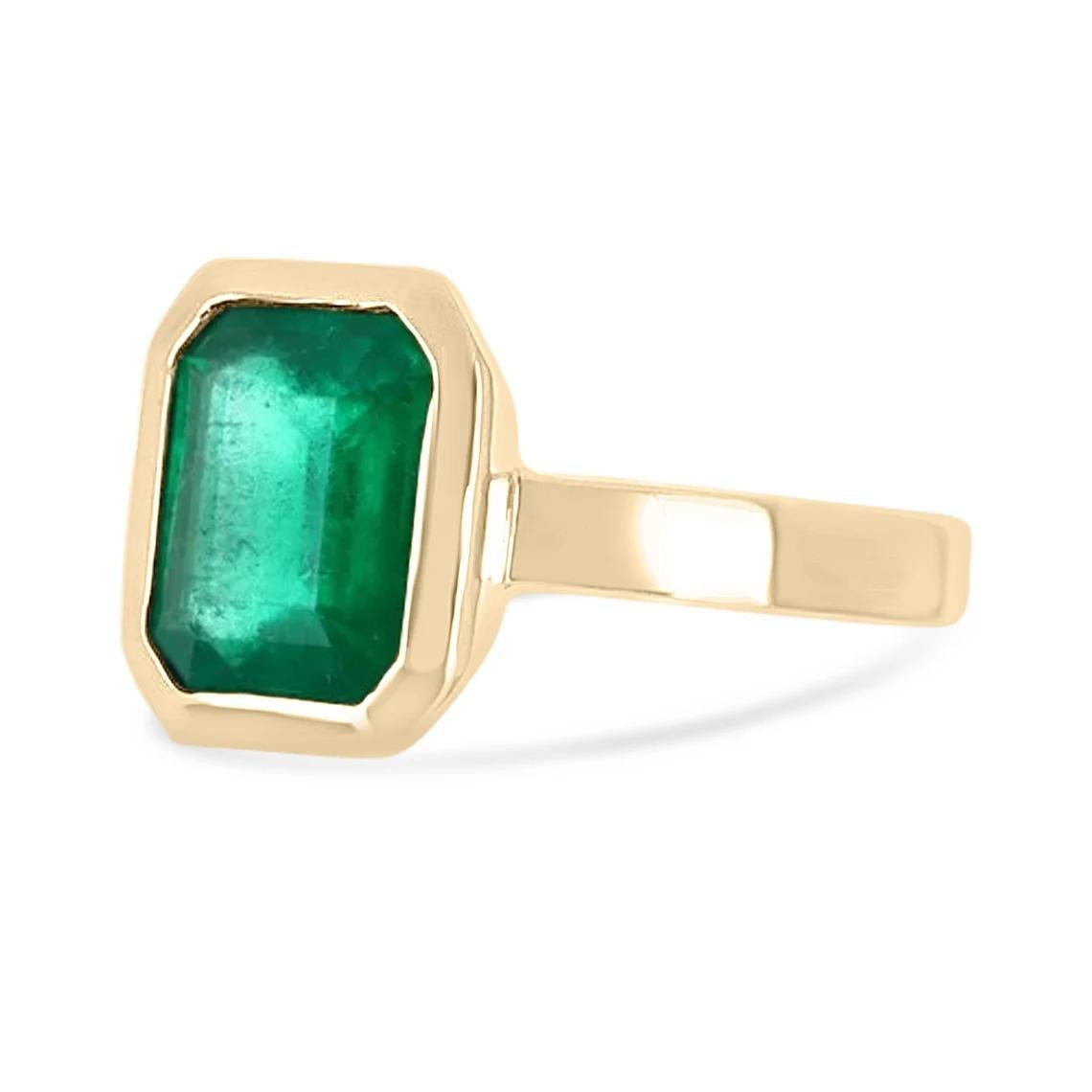 Displayed is a bespoke Colombian emerald solitaire emerald-cut engagement/right-hand ring in 14K yellow gold. This gorgeous solitaire ring carries a 1.90-carat emerald in a bezel setting. The emerald has transparent clarity with minor flaws that are
