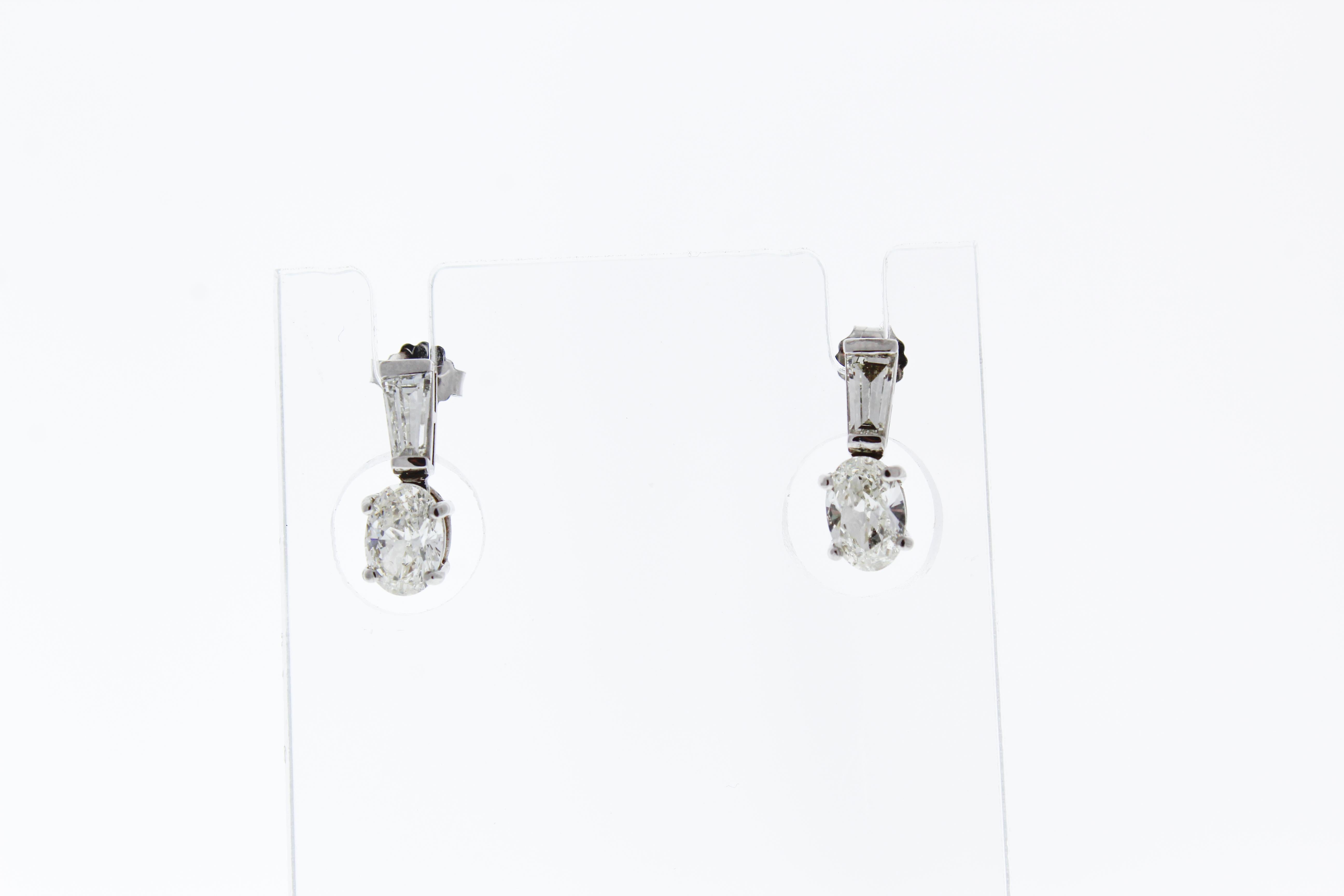These diamond earrings feature two oval diamonds that total up to 1.43carats and two trapezoid cut diamonds that total .47carats. The diamonds are set in 14k White Gold.
