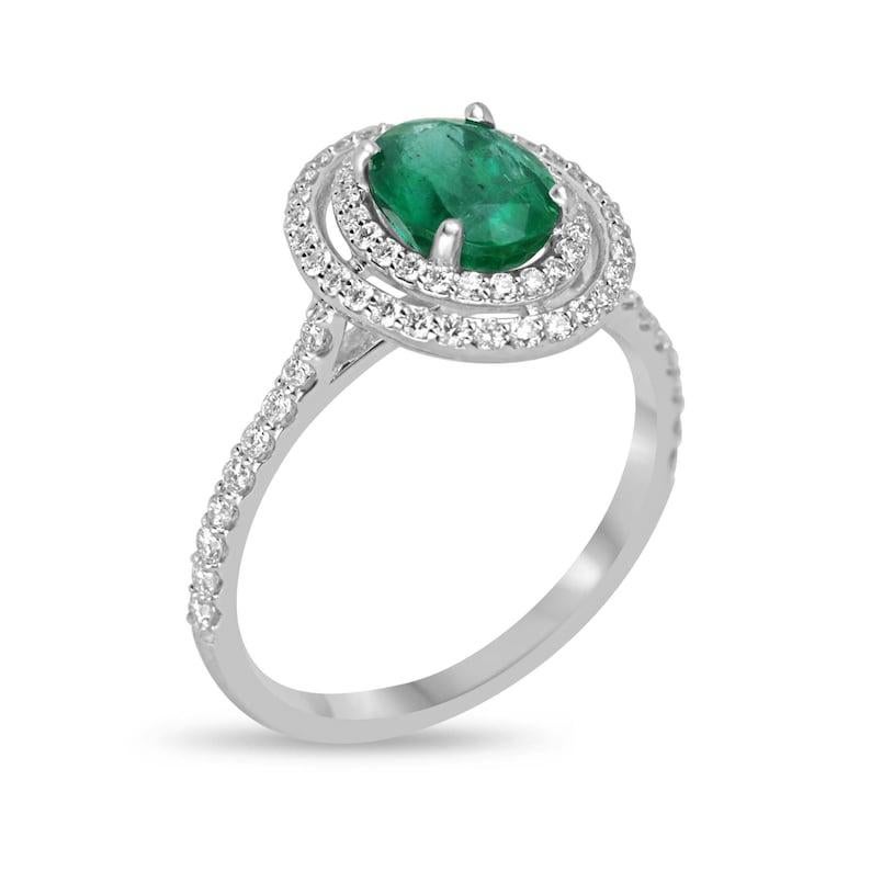 Radiate sophistication with our Emerald and Double Diamond Halo Ring. Featuring a stunning 1.35-carat oval cut emerald from Zambia, known for its rich color and lush vibrancy, this piece boasts a mesmerizing semi-transparent clarity and great