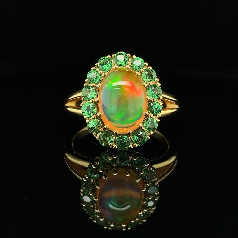 This delightful ring pairs a beautiful Ethiopian opal with lively green tsavorite garnets, creating a gorgeous combination of colors. Sparkling tsavorite rounds highlight the bright “Granny Smith apple” green flashes dancing within the opal, while