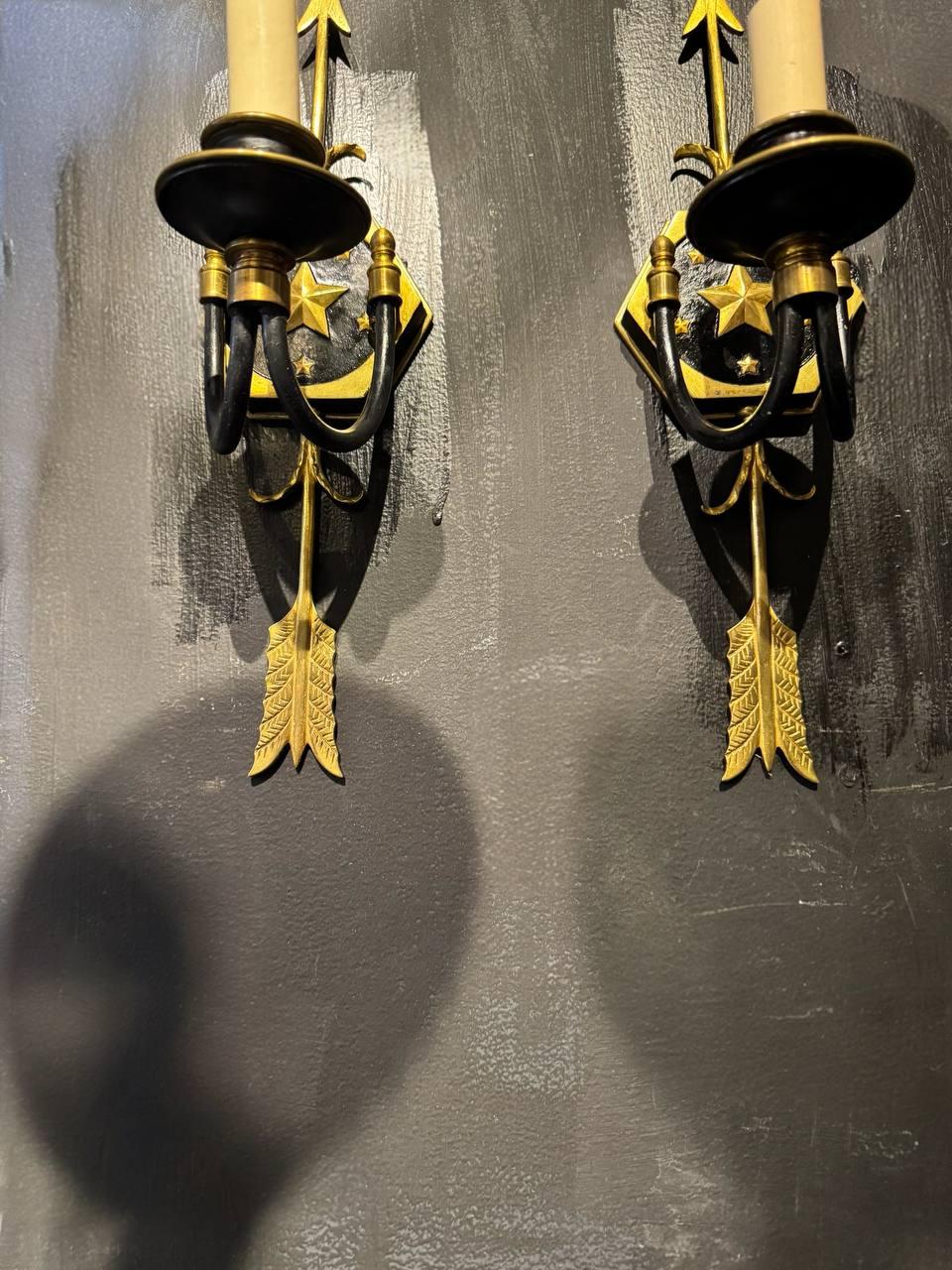 Circa 1910's American style bronze one light sconces with arrows and stars in design. Unusual arm shape