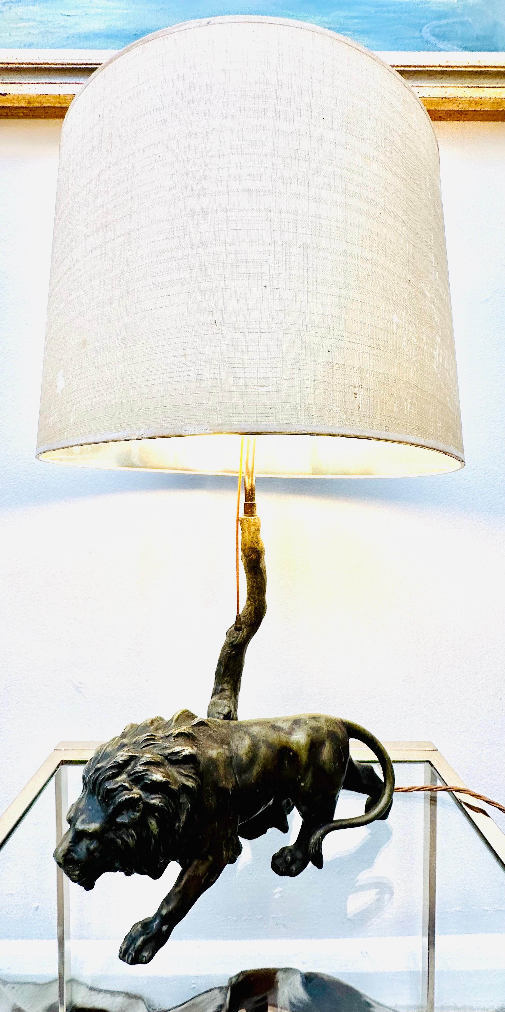 1910s Bronze effect spelter table lamp of lion prowling past a a tree. The original shade is balanced at the top of the tree and secured in place with a feature brass finial. The table lamp would make a rather quirky addition to any living or dining