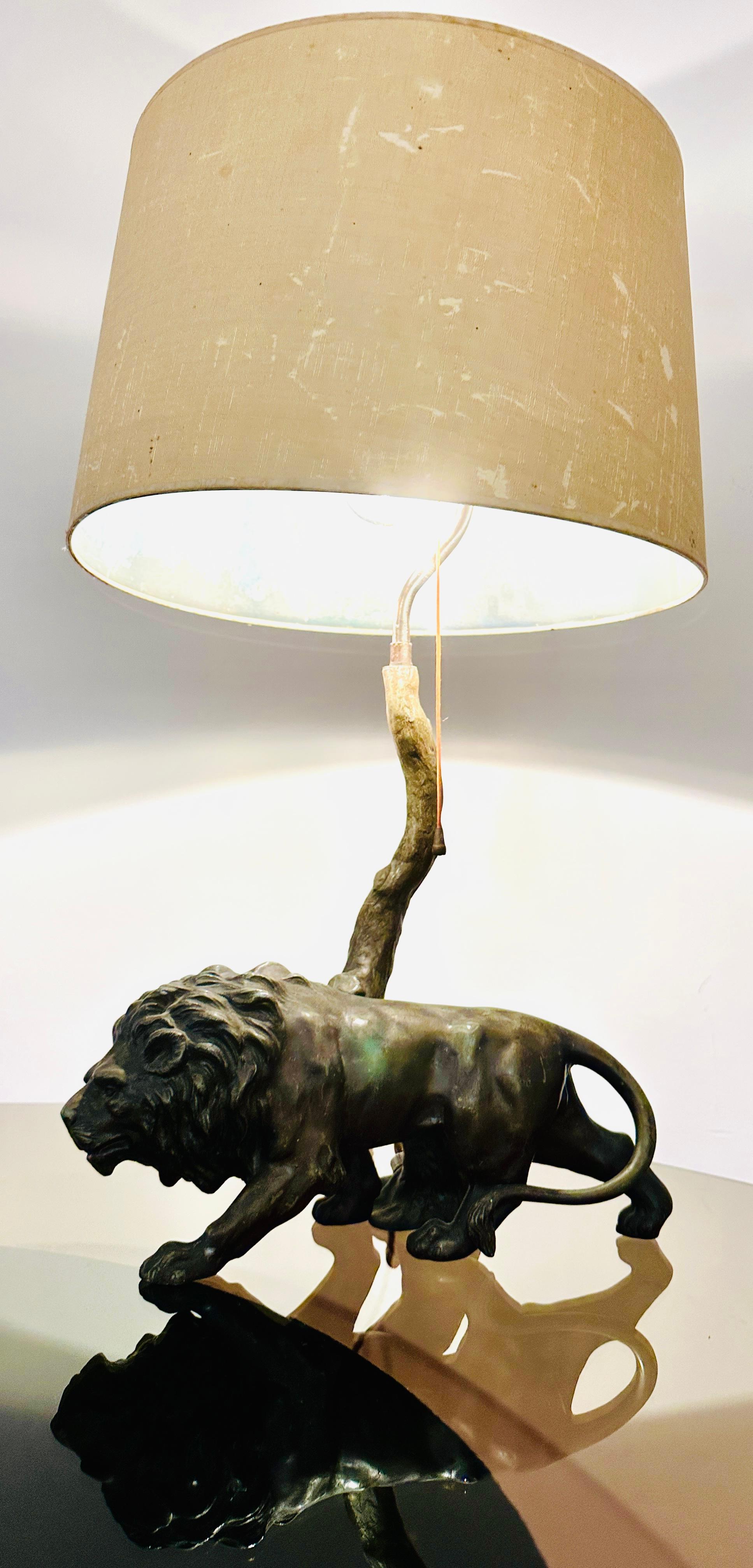 1910s Bronze effect spelter table lamp of lion prowling past a a tree. The original shade is balanced at the top of the tree and secured in place with a feature brass finial. The table lamp would make a rather quirky addition to any living or dining