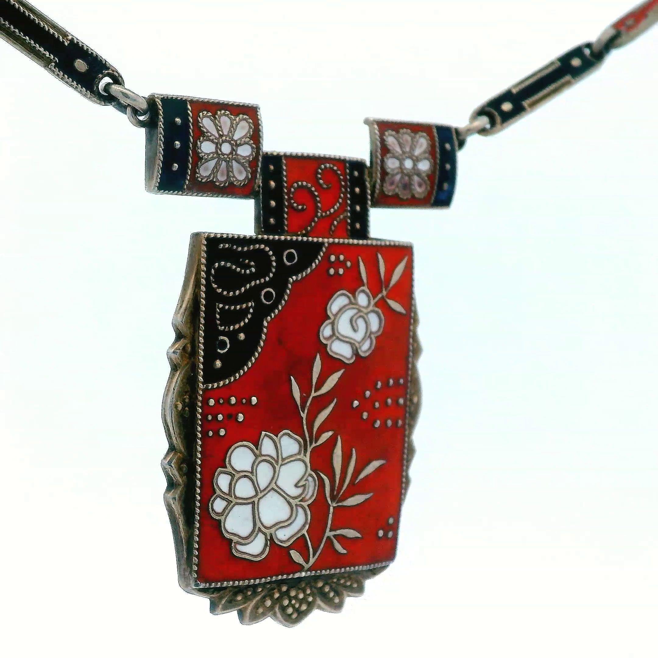 Diese schöne Halskette stammt aus dem Jahr 1910 und ist aus Sterlingsilber mit roter, schwarzer und weißer Emaille gefertigt. Das Besondere an dieser Halskette sind die detailreichen Blumenporträts, die durch die prächtigen Emaillefarben möglich