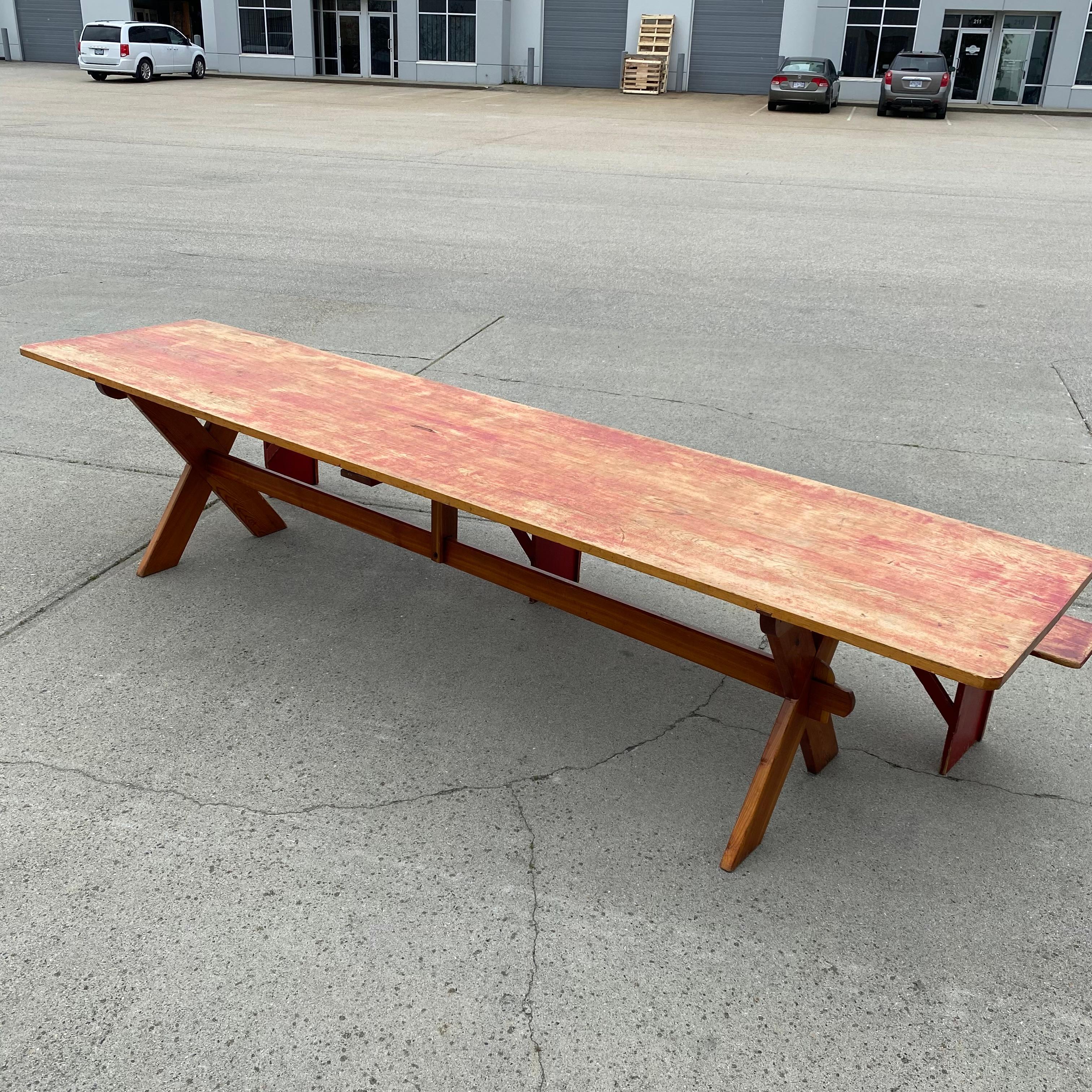 Iconic Canadian prairie saw buck table in pine retaining red original  paint on a two board plank top in classic country style base.. These long tables were documented by Canadian researchers as Hutterite made and presumed usage was large harvest
