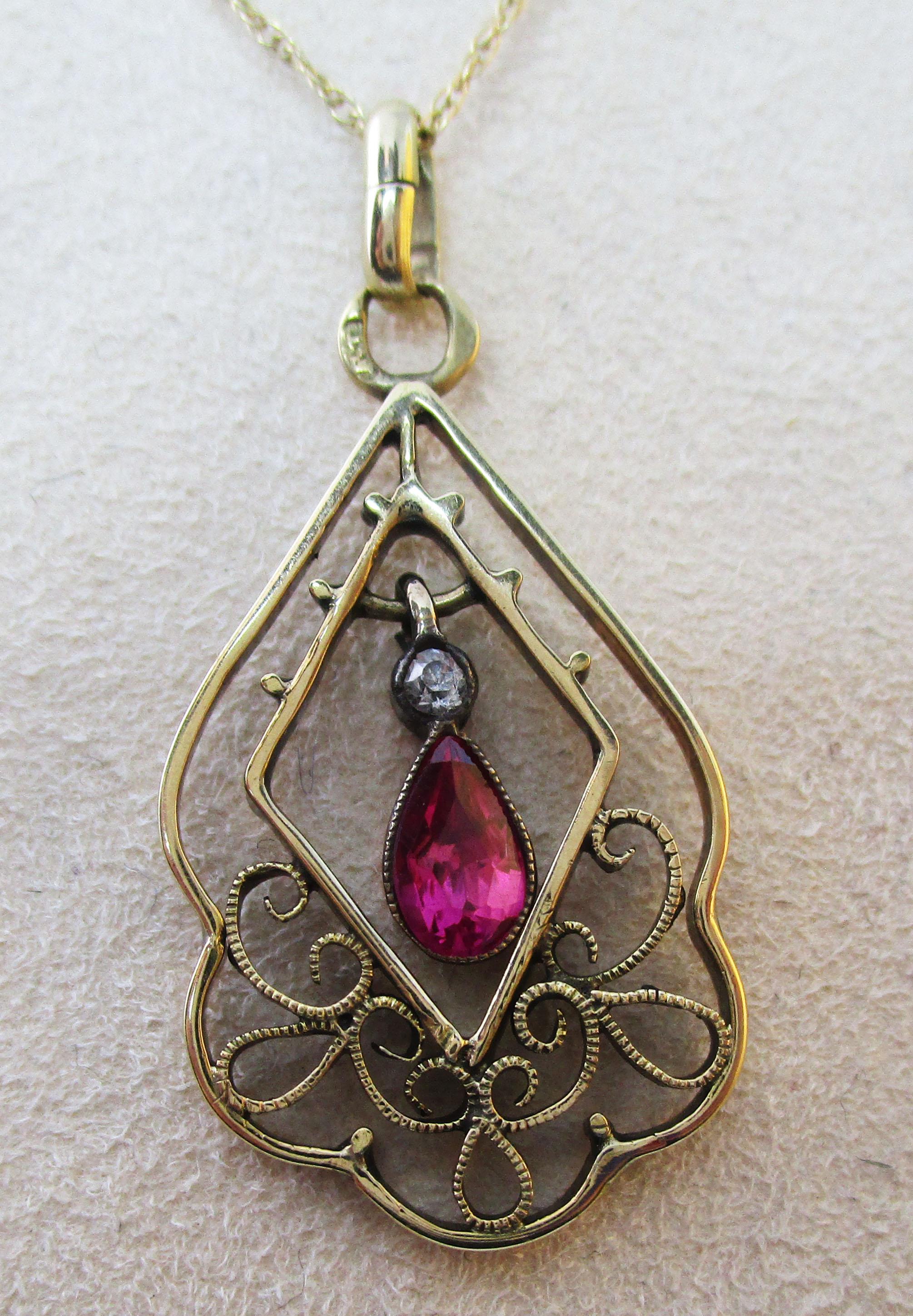 This is a stunning Edwardian Austrian pendant from 1910 in 14k yellow gold featuring a stunning red ruby center and a gorgeous old mine cut diamond accent! The pendant has a delicate, arching open design that is reminiscent of fine lace. The