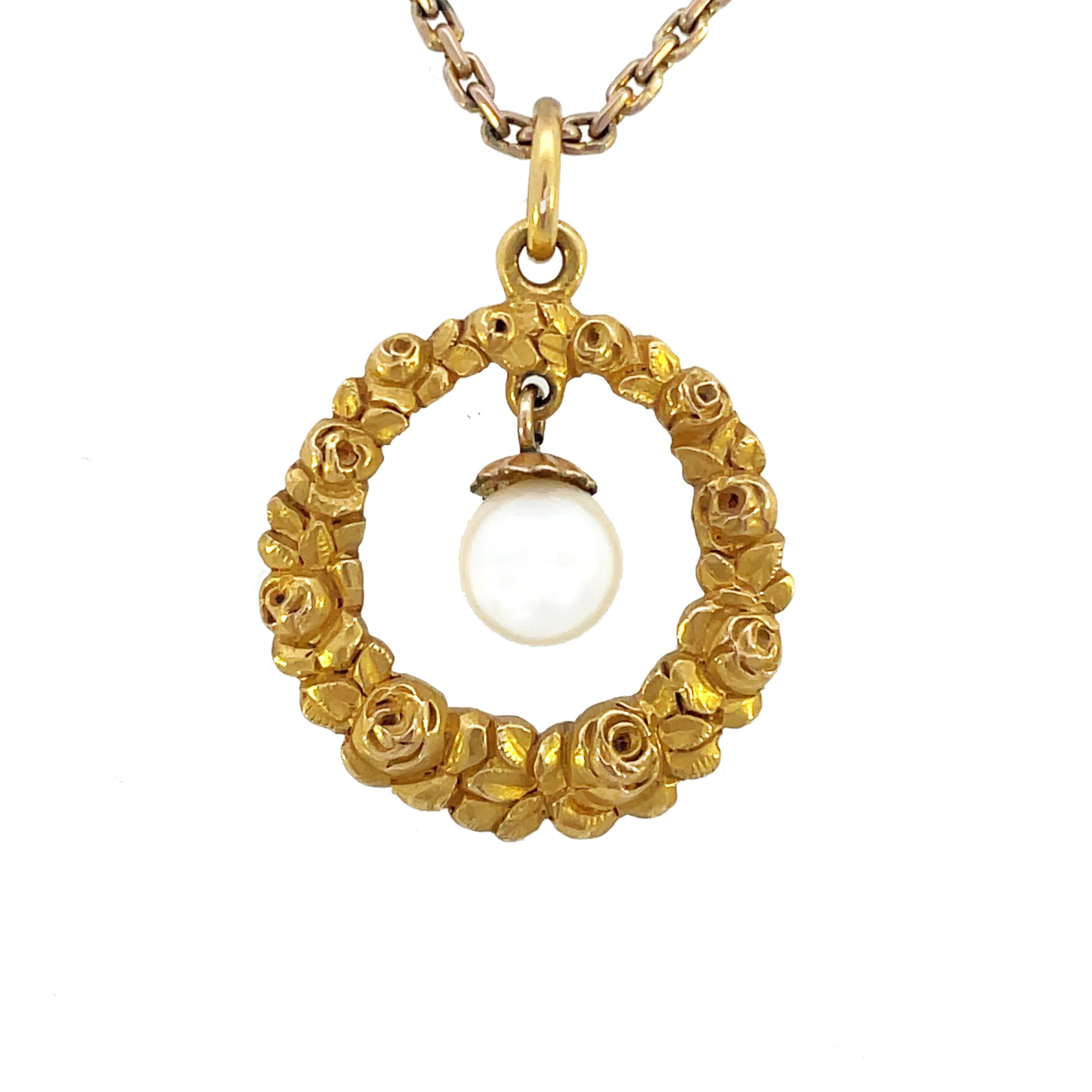 This is an exquisite Edwardian pendant crafted in glowing 14K yellow gold that features a lovely rose motif framing an articulated pearl at the center. This pendant is elegant and classy and would be an excellent addition to your jewelry wardrobe.