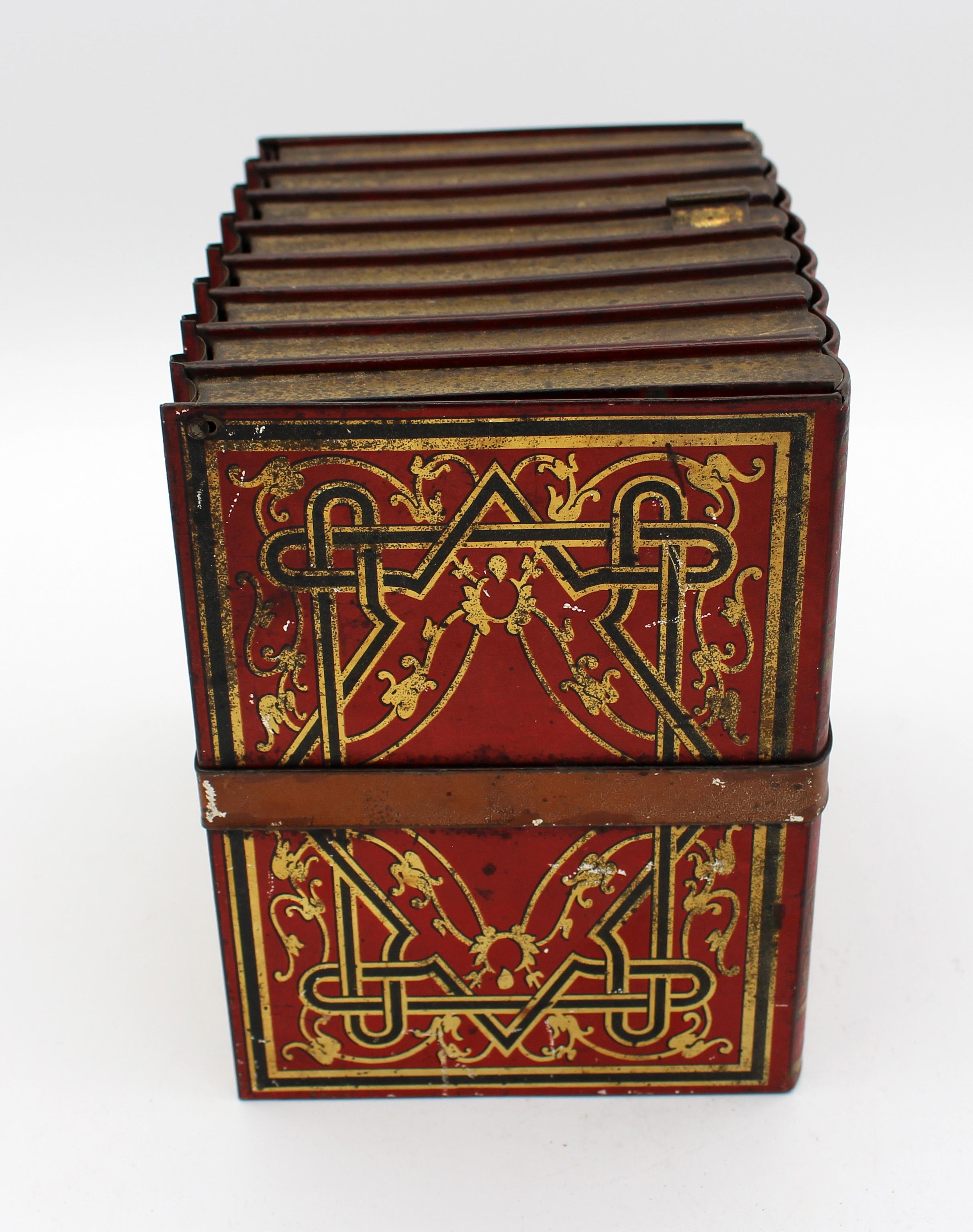 Faux books biscuit tin box by Huntley & Palmers, 1910, English. In the form of a strapped group of generic books old red & black paint with gilt work and tan strap. Overall wear commensurate with age & use.
6.5