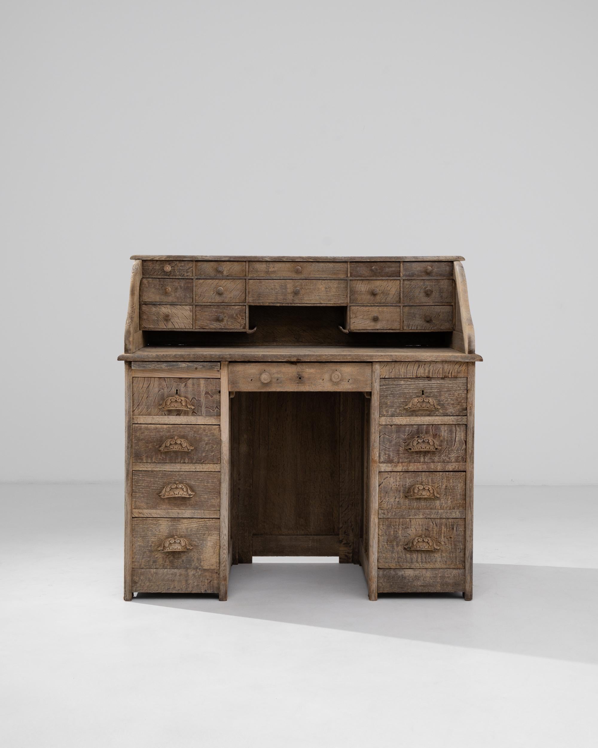 This oak escritoire offers a secluded workspace. Built in France circa 1910, contoured partitions shield the desktop, creating a bubble of privacy ideal for personal correspondence and focused thought. Above the tabletop, an array of small drawers