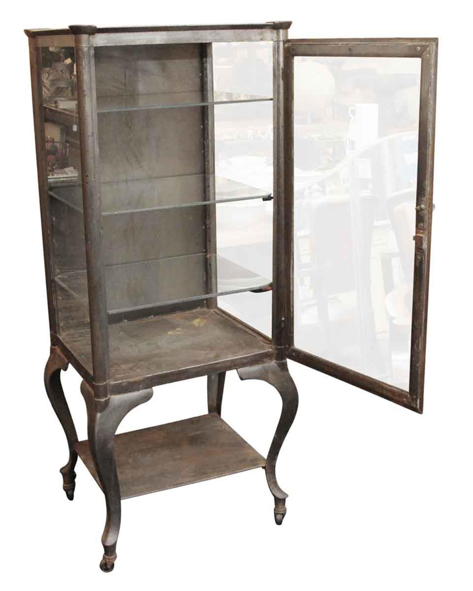Early steel medical cabinet that has been stripped and lacquered with cabriole legs, circa 1910. It has a metal back with glass sides and 3 glass shelves in addition to a bottom shelf. This is a great piece for storage in a kitchen or bathroom or a