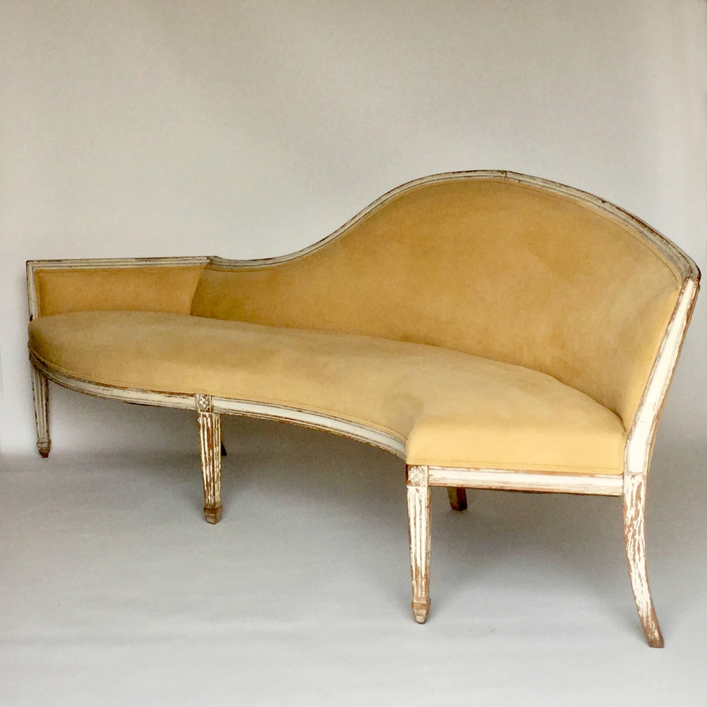 Antique French Louis XVI carved walnut settee, painted finish worn with age, unusual sinuous shaped design, reupholstered in buff colored ultra suede with a tiny whole near the back of the seat, square fluted tapering legs with floral rosette