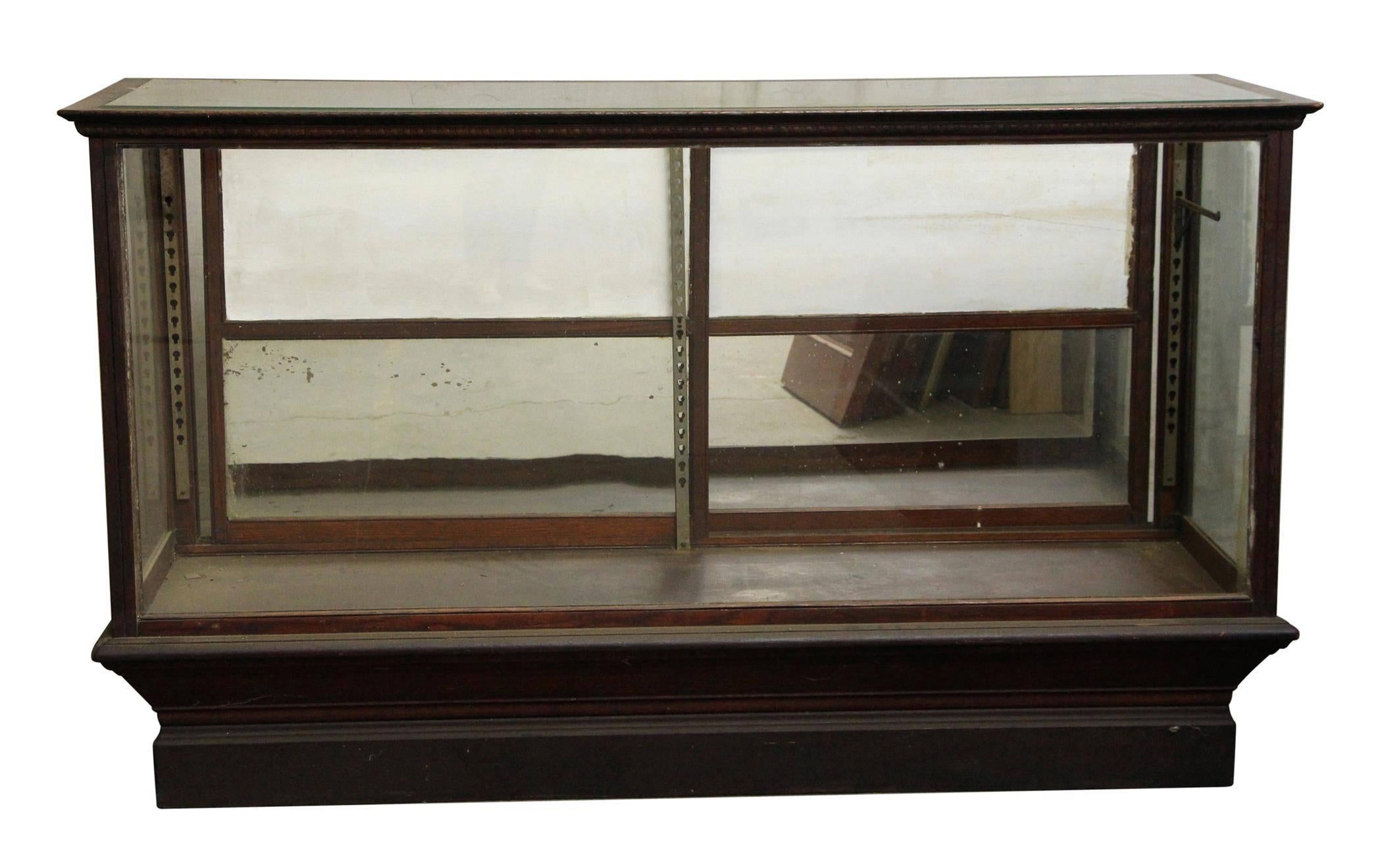 Oak display case with sliding glass doors and egg and dart trim design. Nice size! Features a mirrored glass back on the two lower panels and replacement panels on the upper two. The bracket system is adjustable, but only two brackets are included.