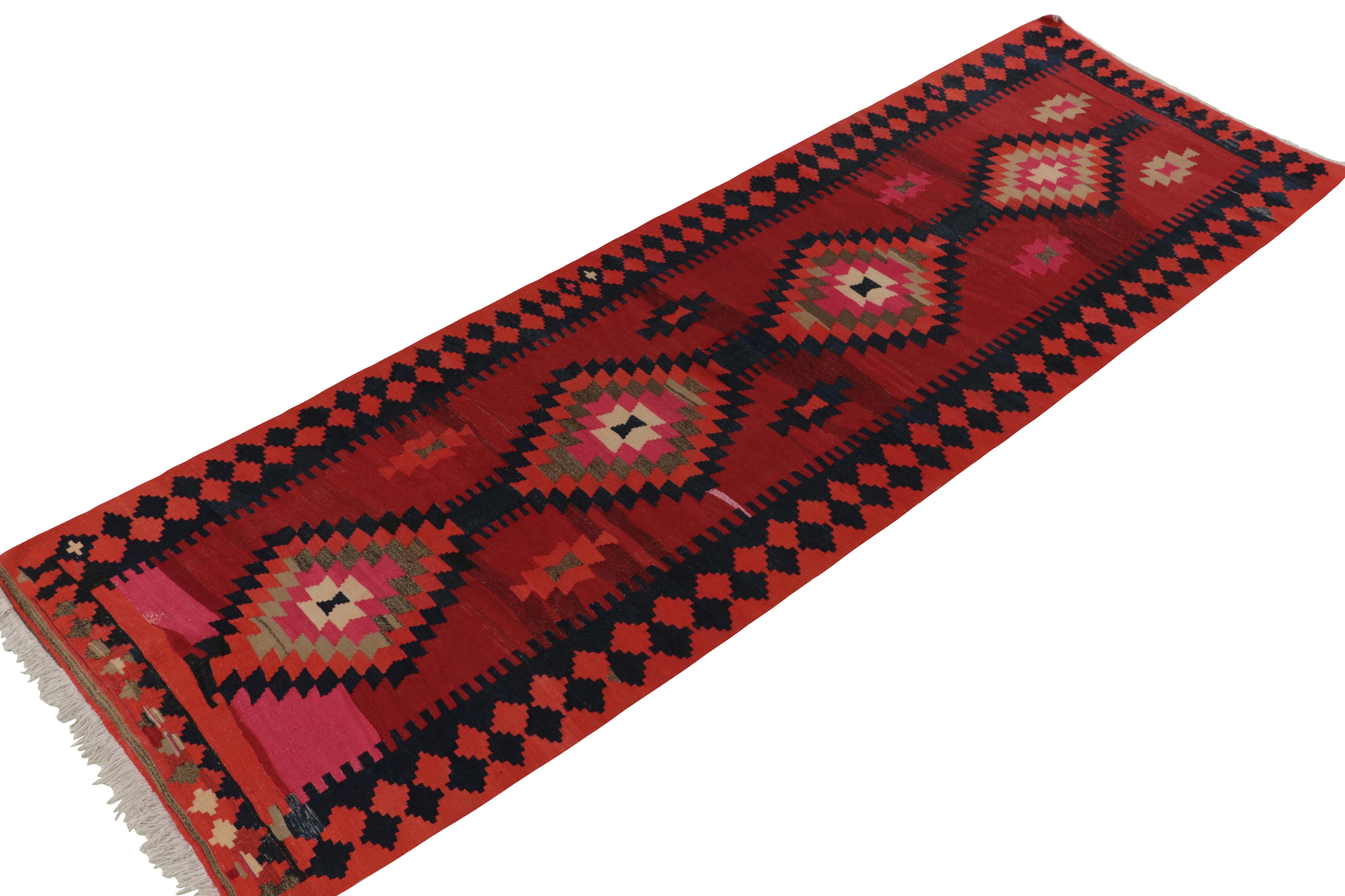 Handwoven in wool circa 1920-1930, this 4x12 antique Persian Kilim exemplifies the richest colors and most classic tribal aesthetic alike. This particular piece enjoys a serrated field pattern in rich red and vibrant pink, punctuated by a rare