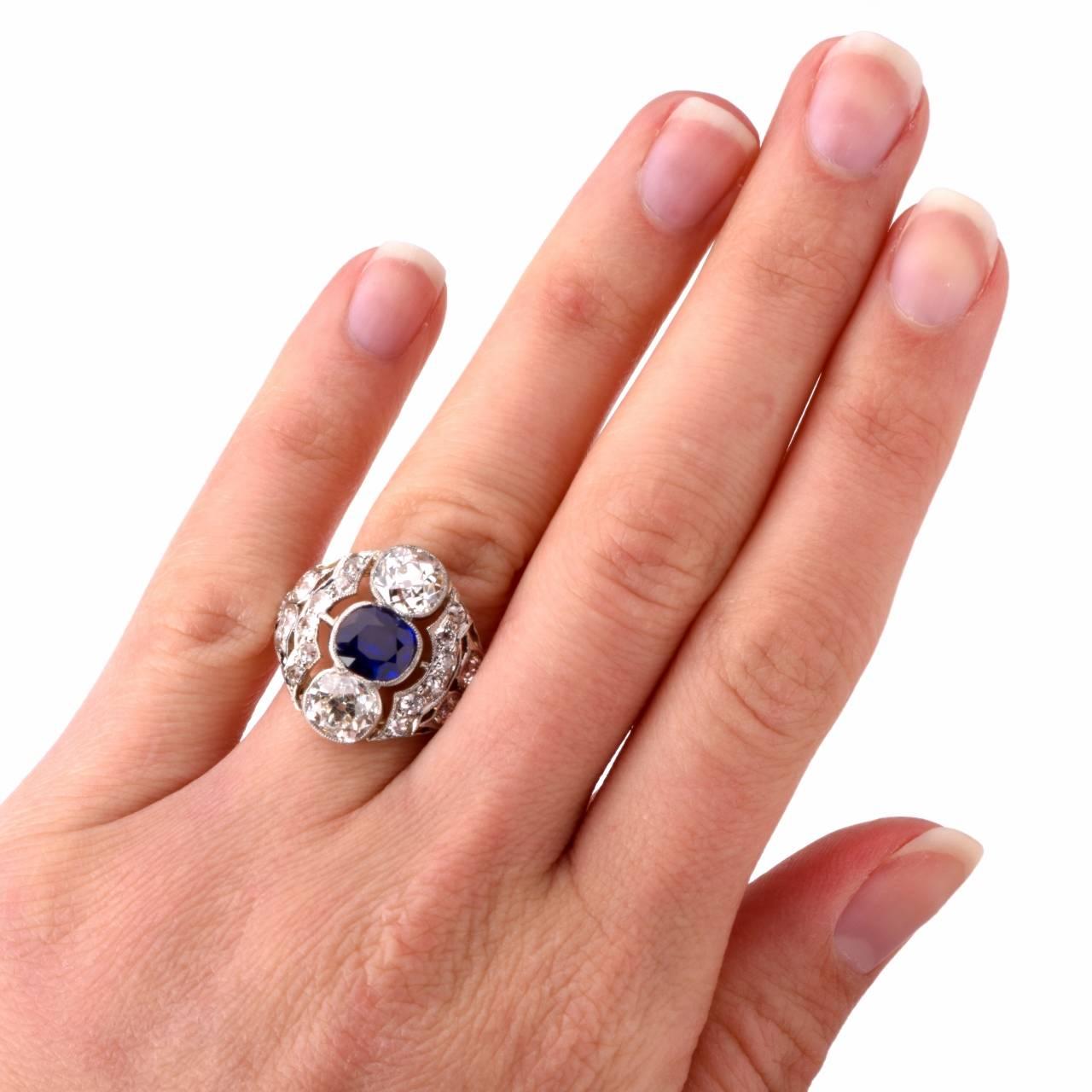 This antique Art Deco ring of fascinating aesthetic attraction is crafted in solid platinum, weighs 4.8 grams and measures 17 mm wide. Designed as a stylized lozenge plaque, this fascinting ring exposes at the center a 1.65 ct cushion-cut blue