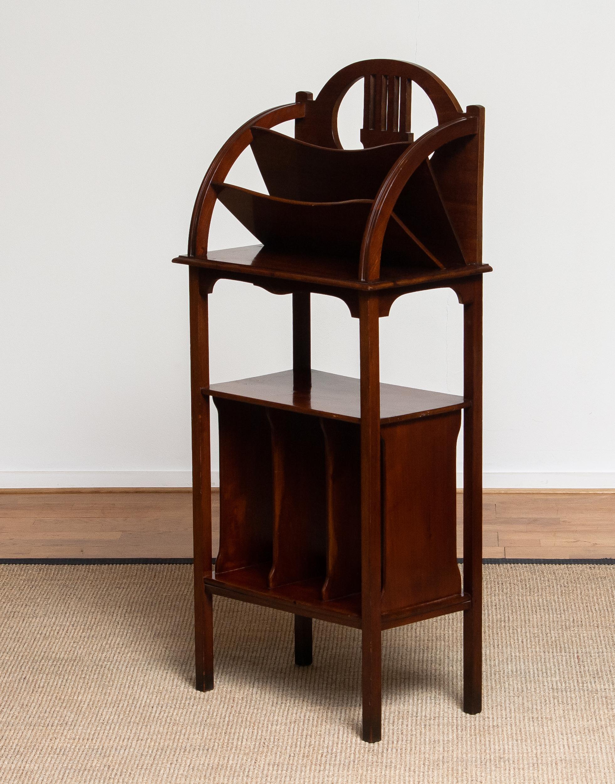 Swedish elegant Art Nouveau period magazine and newspaper rack from the 1910s, crafted in rich mahogany. The design features graceful curved lines and functional compartments for organizing reading materials, showcasing the refined craftsmanship and