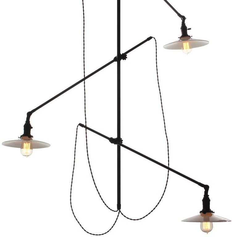 A hanging, antique industrial ceiling-mount light fixture with three adjustable arms. Signed on ceiling rosette, this fixture has a dark blackened finish and the original vintage milk glass disk shades. The overall drop can be customized.