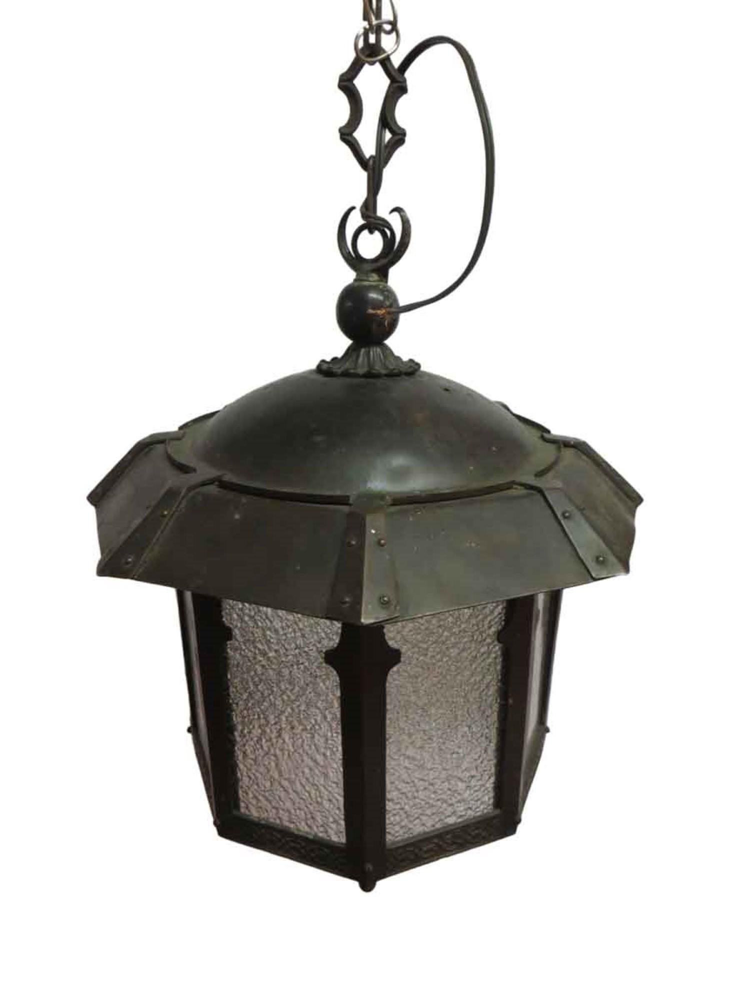 1910s Arts & Crafts copper pendant lantern with hand hammered details and textured glass commonly used in a foyer or small area. This is missing two small finials at the bottom. Pictured here as is. Price includes restoration. This can be seen at