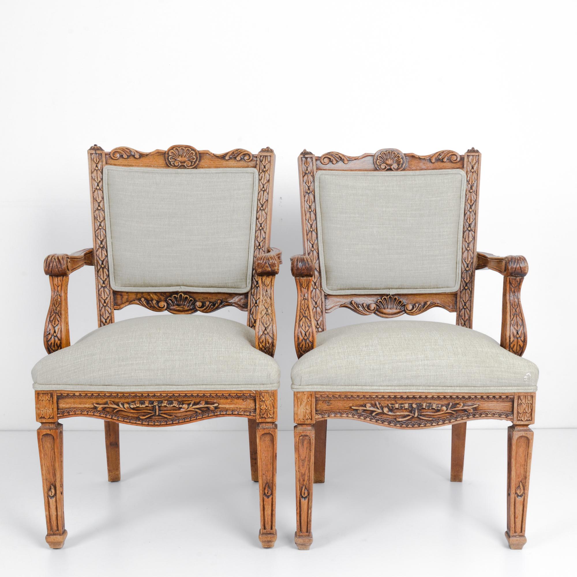 This pair of wooden armchairs was made in Belgium, circa 1910. The chairs have been renewed with a comfortable upholstered seat and back. With the patterned and decorative carvings of foliage and scallop shells, the chairs will infuse a sense of