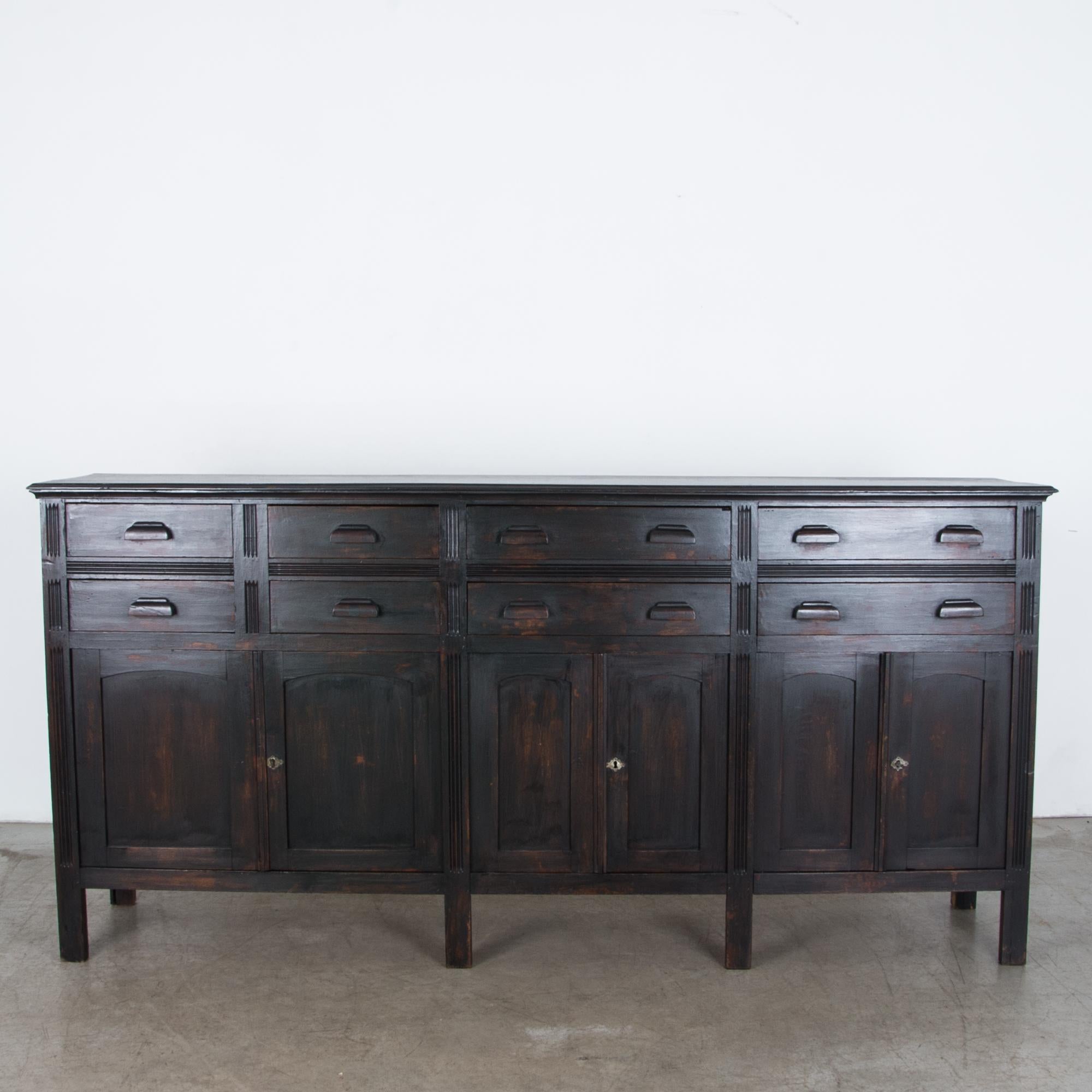 Produced in Belgium circa 1910, this spacious six door storage cabinet features interior dividers and a double row of drawers. A refined construction is simple and direct, with a subtle geometric carved frame. Constructed from durable old growth