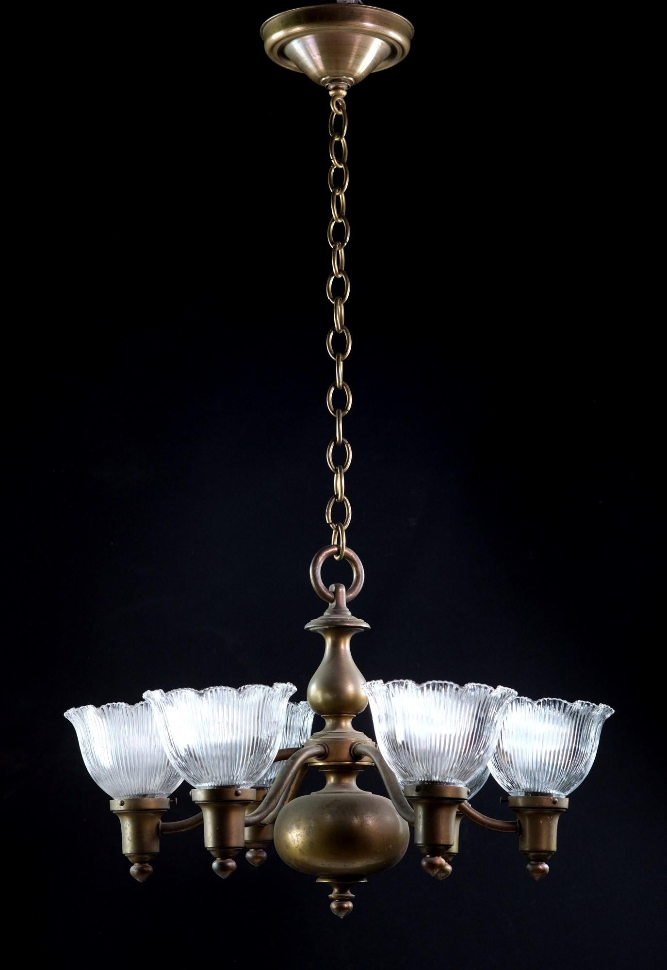 Heavy cast bronze pendant light with original patina and ruffled holophane glass shades. This chandelier is original to the 1910's and consists of 6 lights which come rewired. The price includes cleaning and rewiring while leaving the natural deep