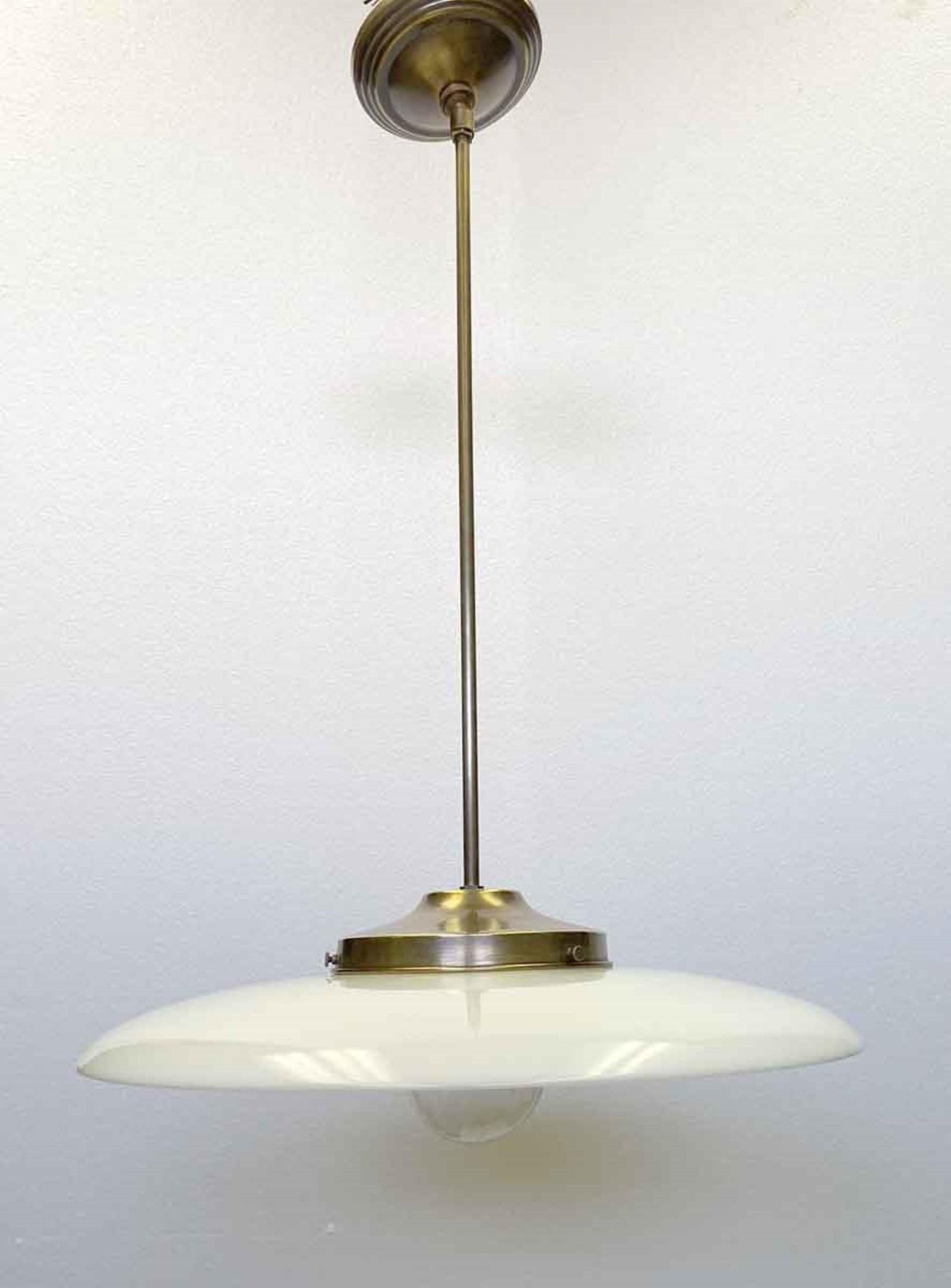 Rare 1910s industrial age curved pancake shaped white milk glass pendant light fitted with a newly wired brass pole fixture. Measures: 17 in. We also can do polished nickel if you prefer. This pairs well with an Edison bulb. Small quantity available