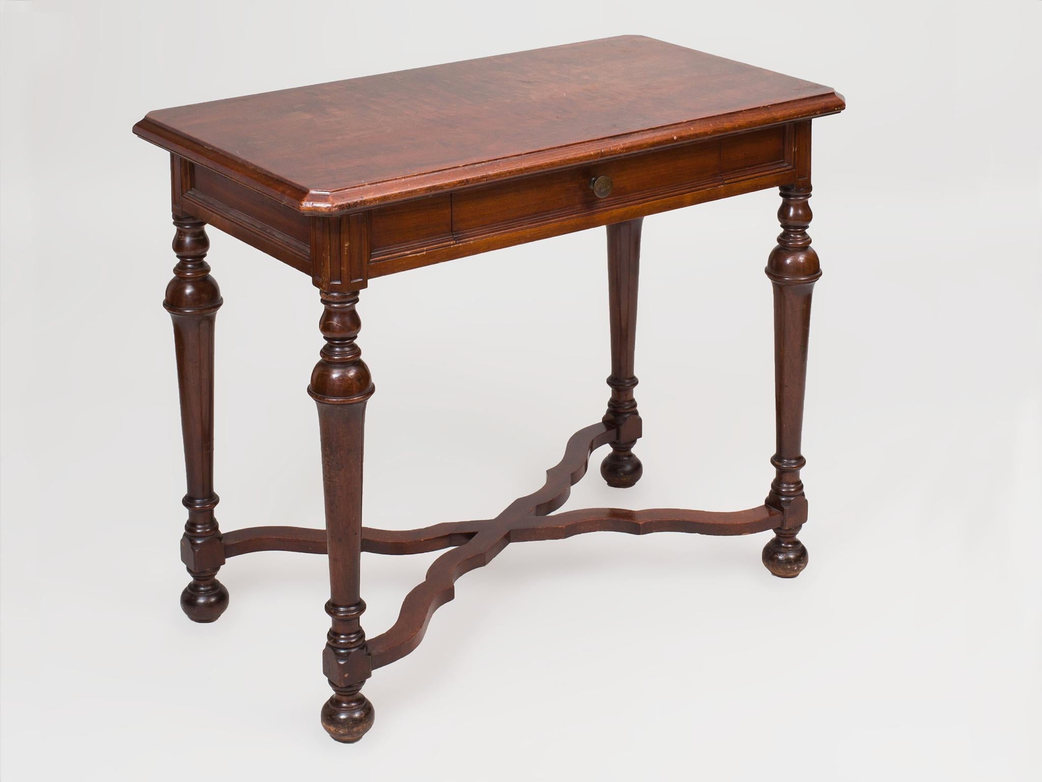 This Victorian style side table was designed and manufactured by the Doten-Dunton Desk Co., circa 1910s. It is comprised of mahogany with a warm, dark glaze finish. The design is elegant and simple: a beveled tabletop, beaded skirt with fitted