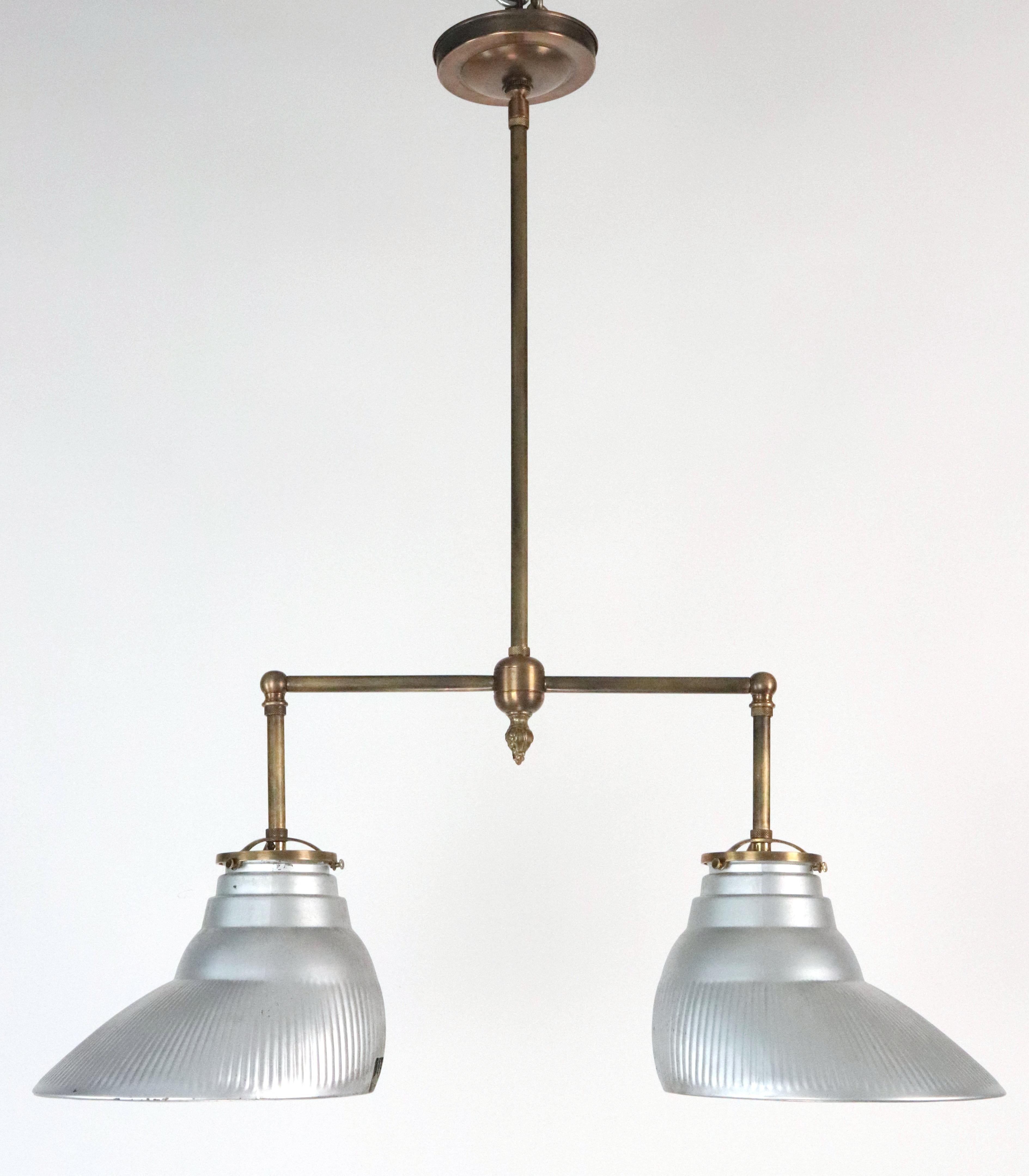 This Industrial style pendant light features a pair of Pittsburgh pentaflector shades mounted on a new antique brass pole fitter. The glass has some minor marks. This requires two standard Edison style medium base bulbs. Cleaned and restored. One