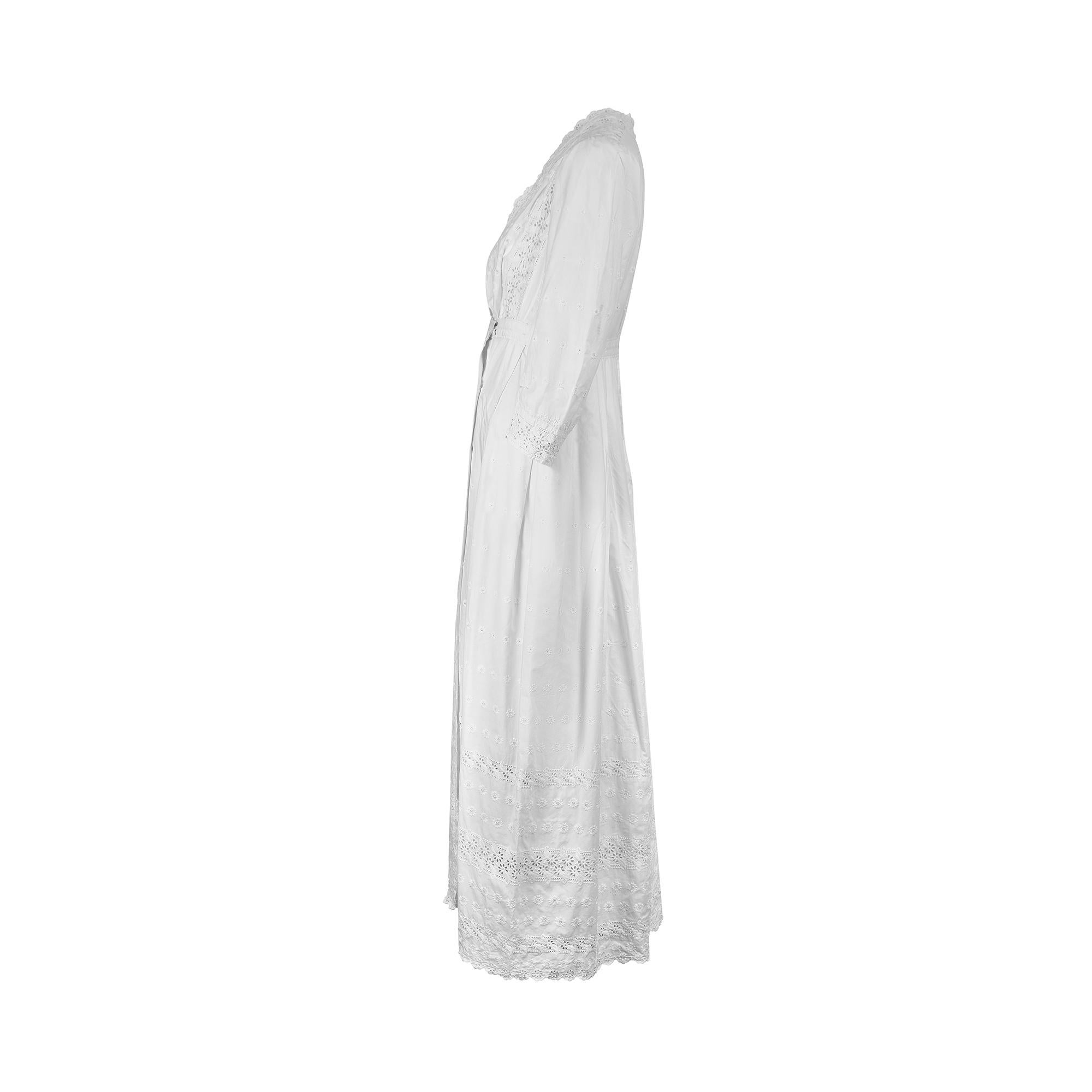 Cette robe ancienne a été créée dans les années 1910 et est en superbe état sans défaut. Le coton reste d'un blanc éclatant et ne porte aucune marque. Il est orné d'œillets découpés à la main et de broderies au point de satin ton sur ton sur