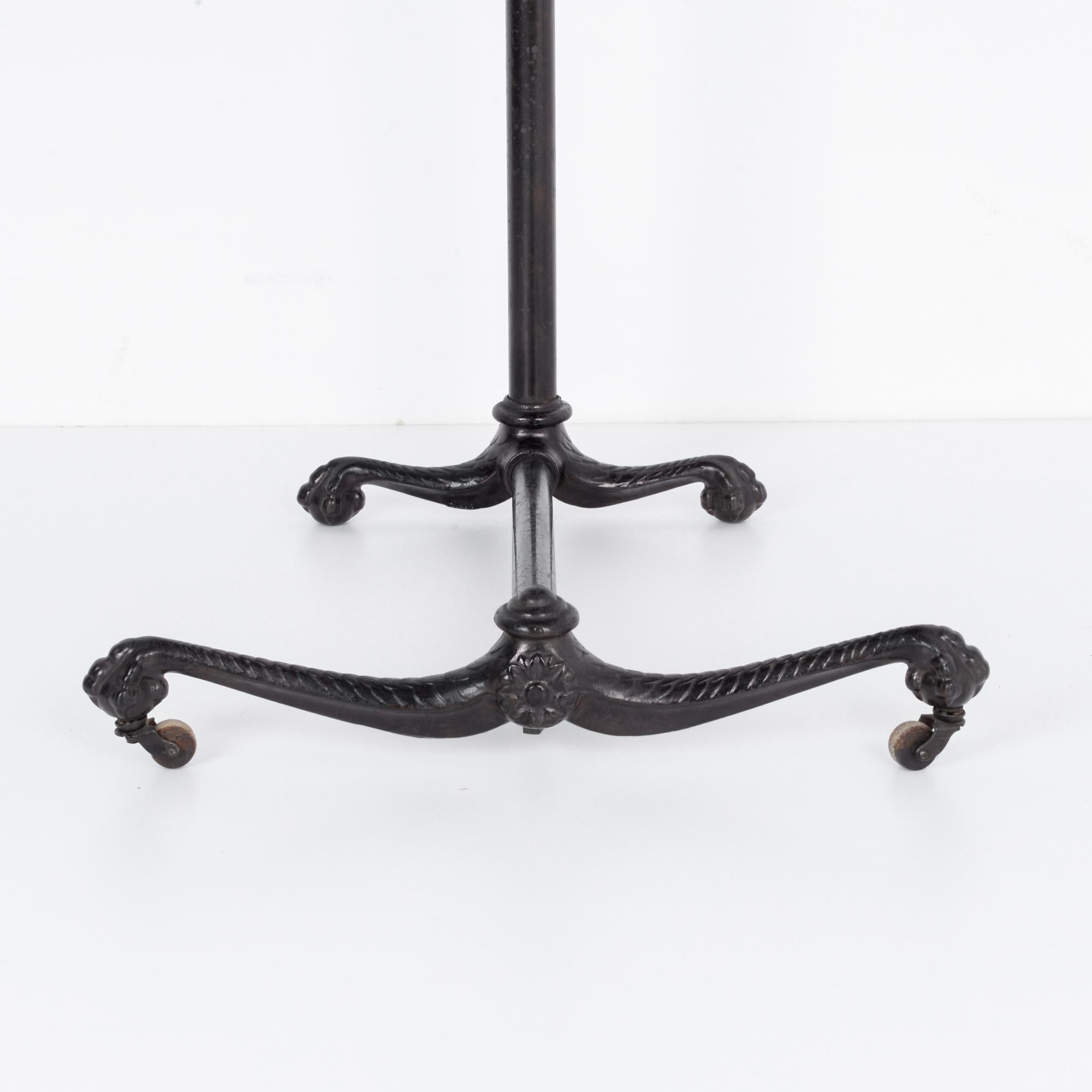 An intriguining small table from France, circa 1910. Standing on four clawed feet resting on balls, rendered in ornamental cast iron with an oak table top. This cozy table is a convenient resting place, height adjustable and comes a set of wheels