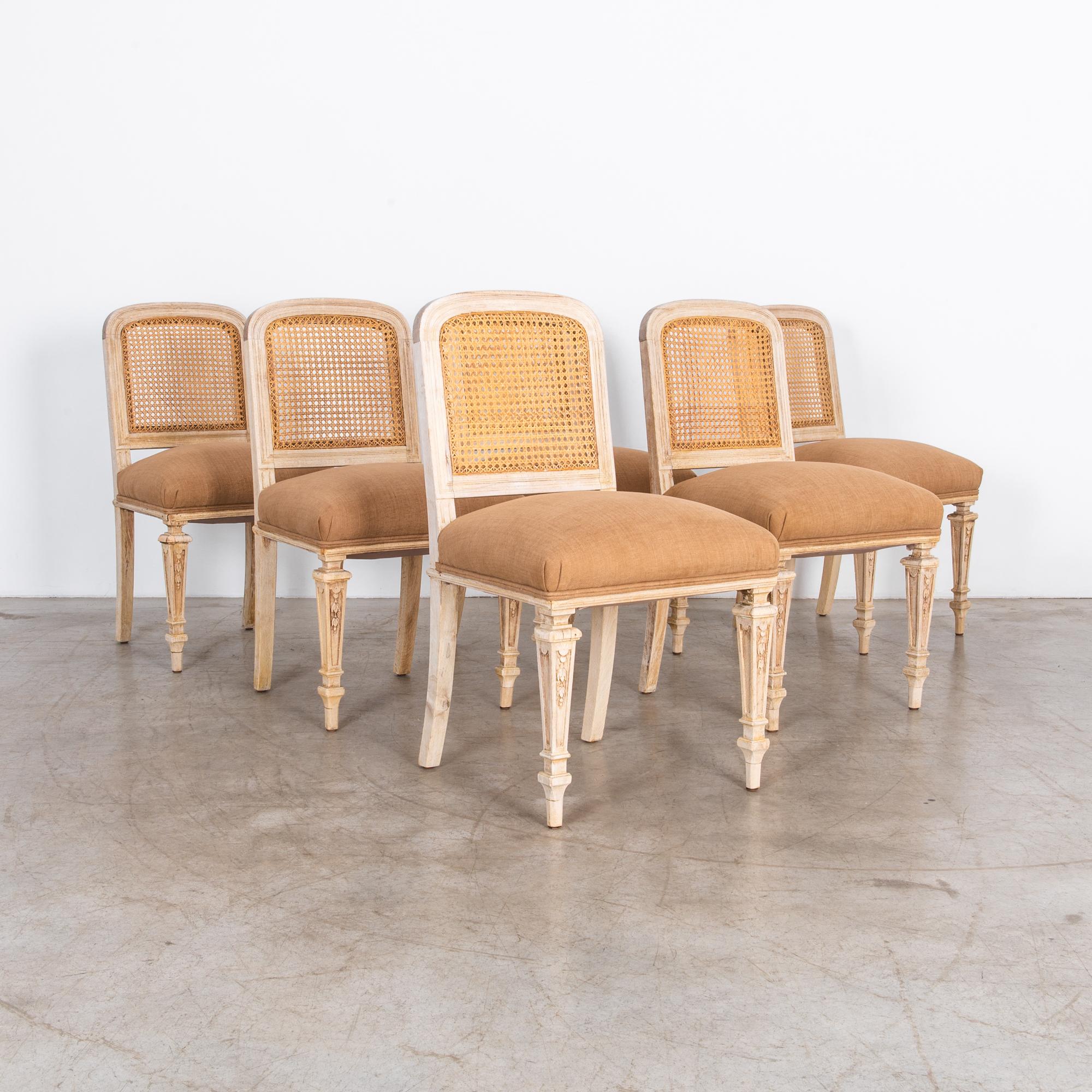 With a warm hue, and comfortable reupholstered seat, these French dining chairs are formal yet inviting. Solid oak frame and woven seat back, the natural materials blend ochres colors, emphasised by the cotton-linen fabric seat. Carved details and