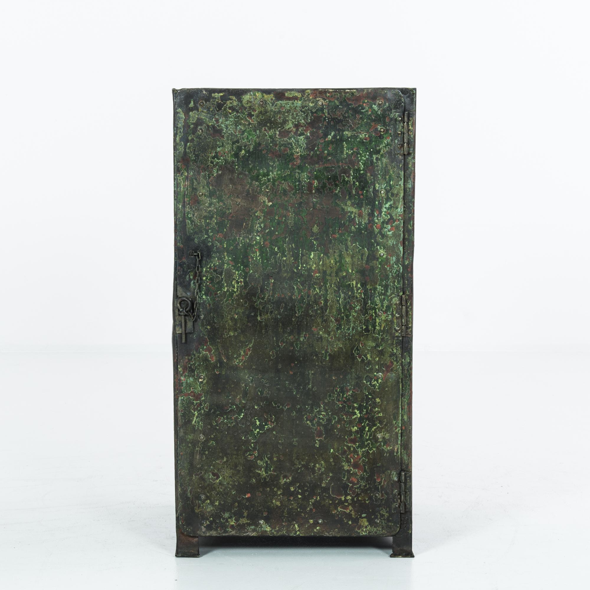 A metal cabinet from France, produced circa 1910. With the posture of a fashionable safe, this little locker breathes life into any staid interior. The green gradient of the original patination of this piece, along with its simple pin closure,