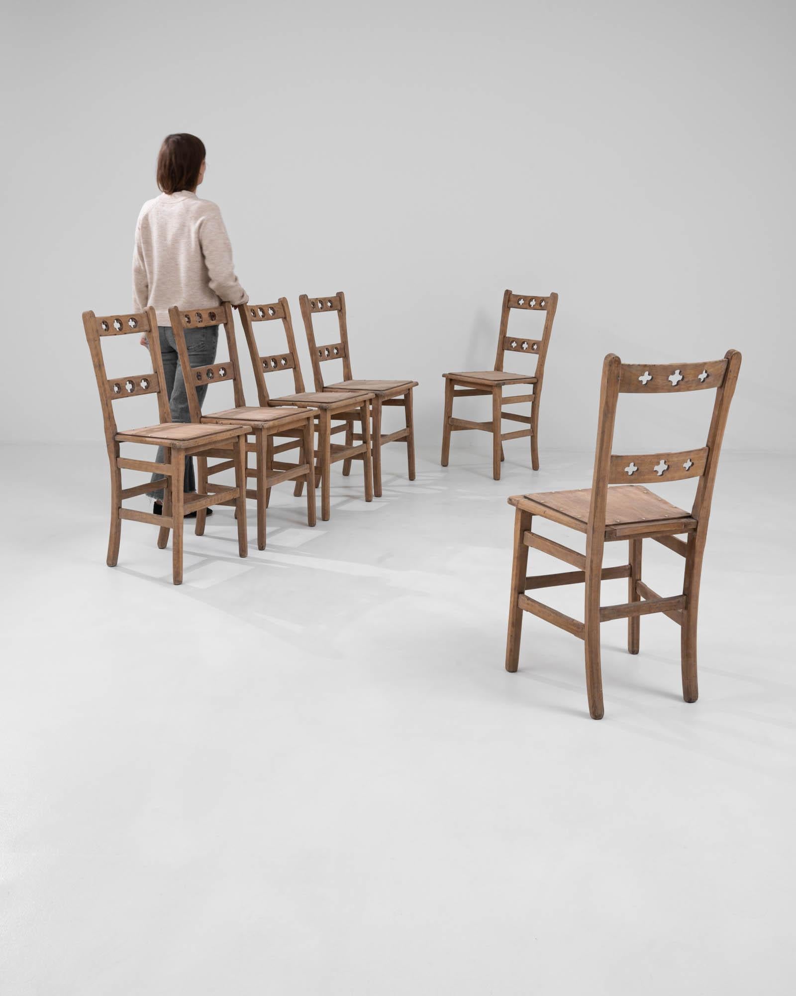 This exquisite set of six 1910s French dining chairs brings a slice of history into your dining space. Crafted from rich, sturdy wood, each chair features a distinctive backrest with charming cut-out details, adding a dash of elegance and character.